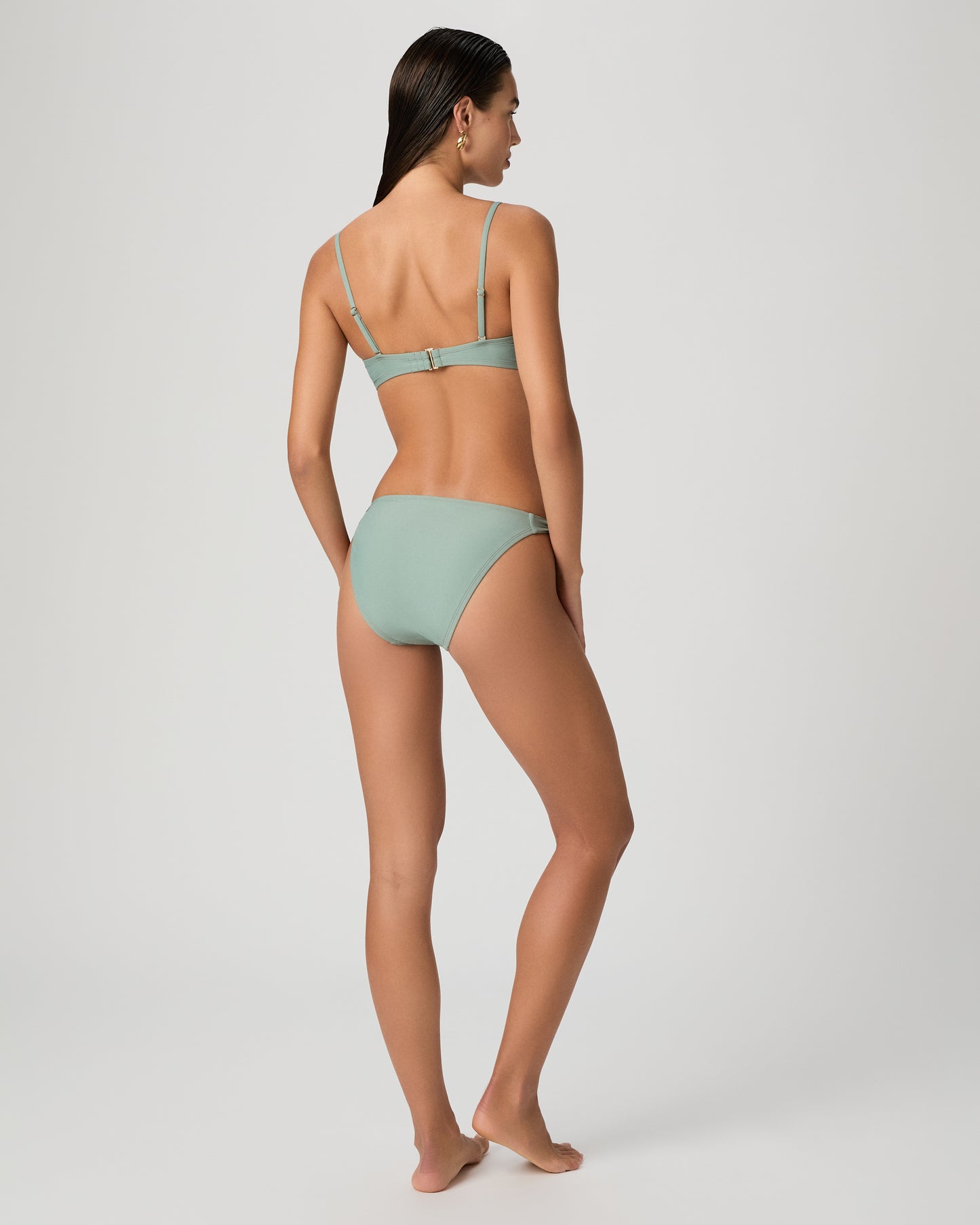 Woman wearing a light green bikini set on a white background