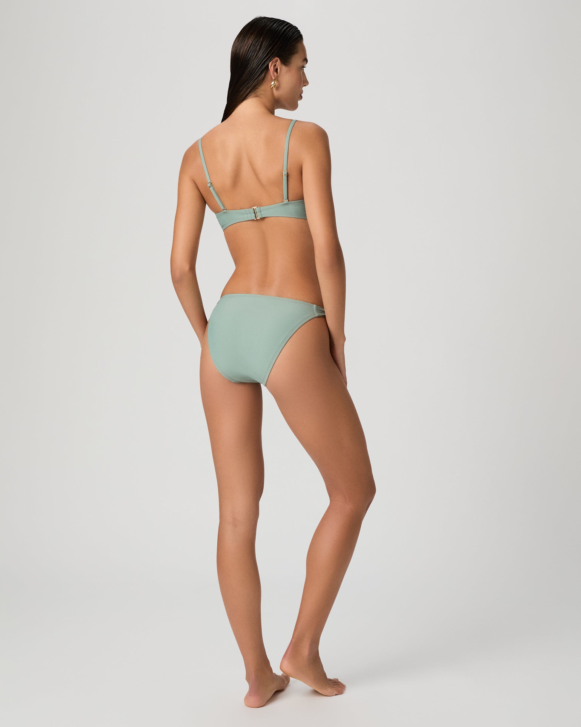 Woman wearing a light green bikini set on a white background