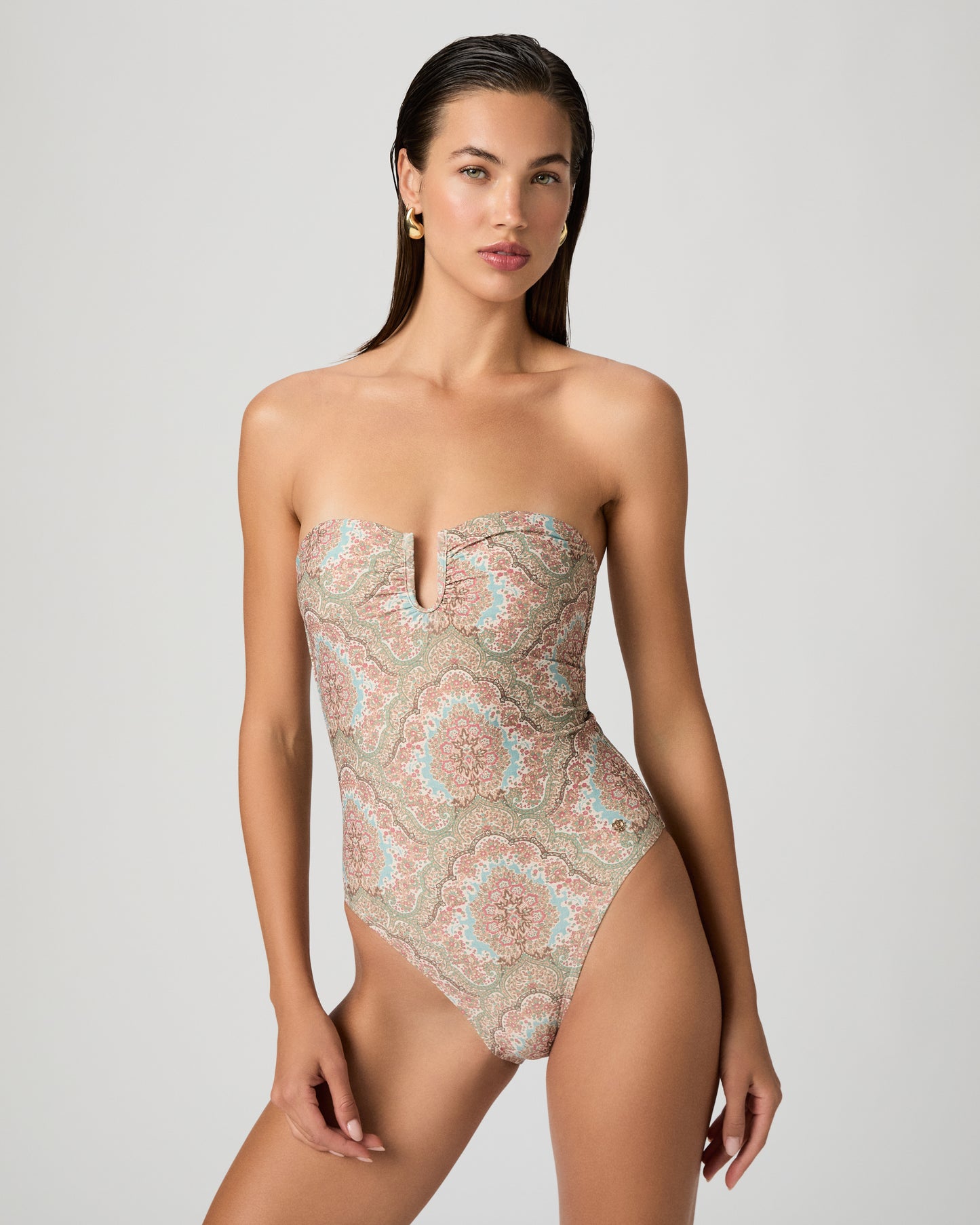 Woman wearing a patterned one-piece swimsuit on a white background