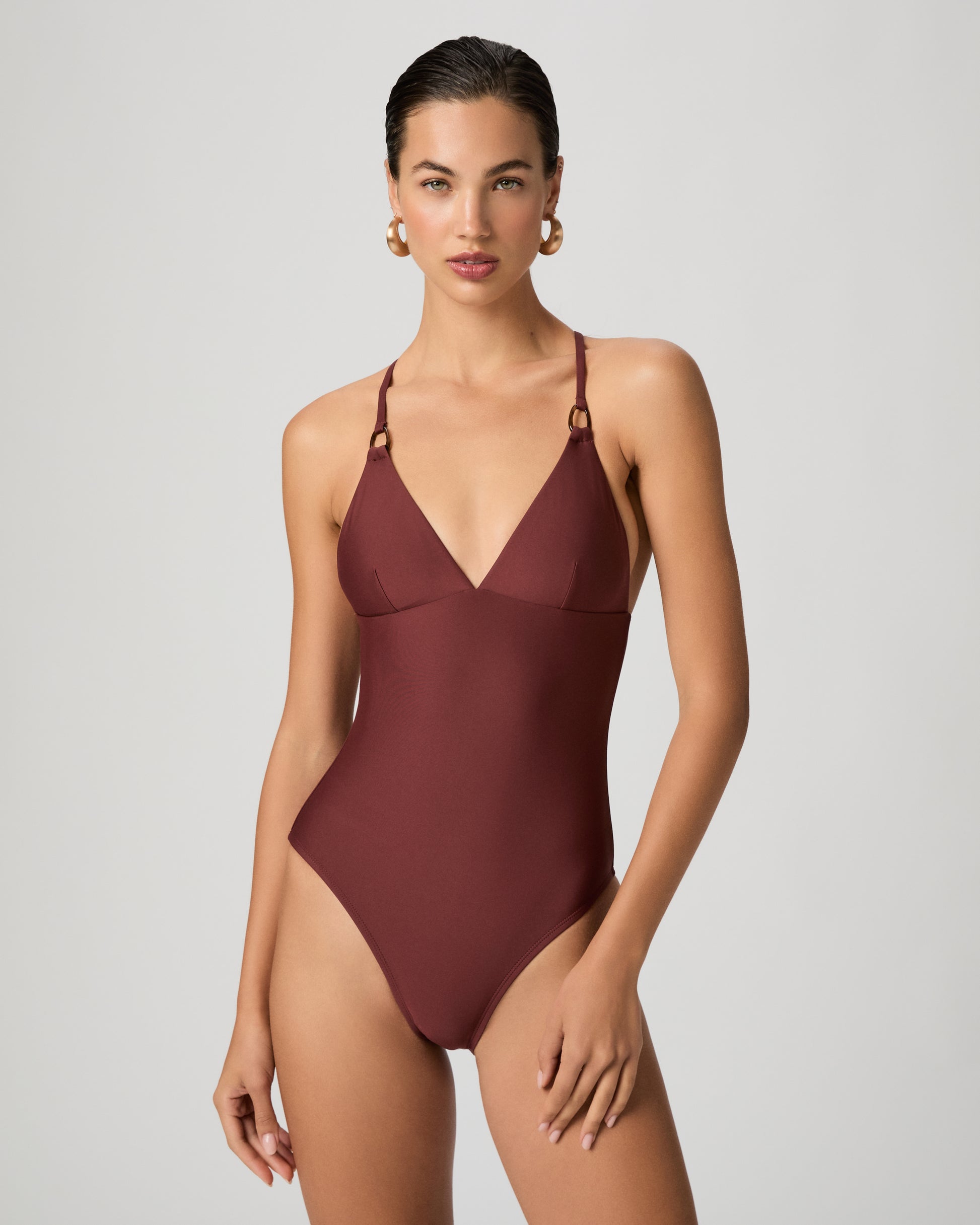Woman wearing a burgundy one-piece swimsuit on a white background