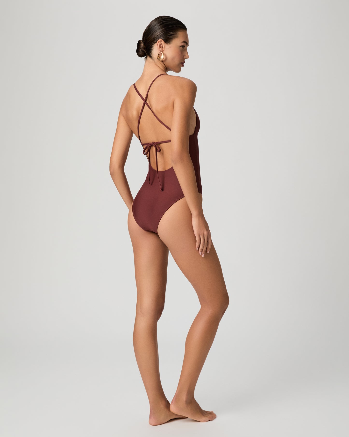 Woman wearing a burgundy one-piece swimsuit on a white background