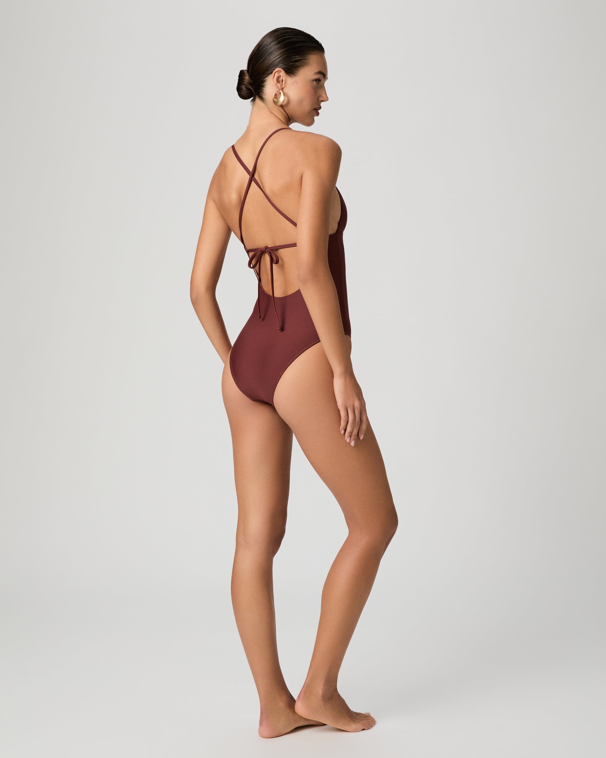 Woman wearing a burgundy one-piece swimsuit on a white background