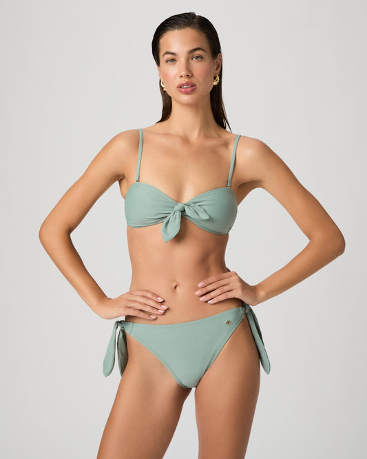 Woman wearing a light green bikini against a plain background