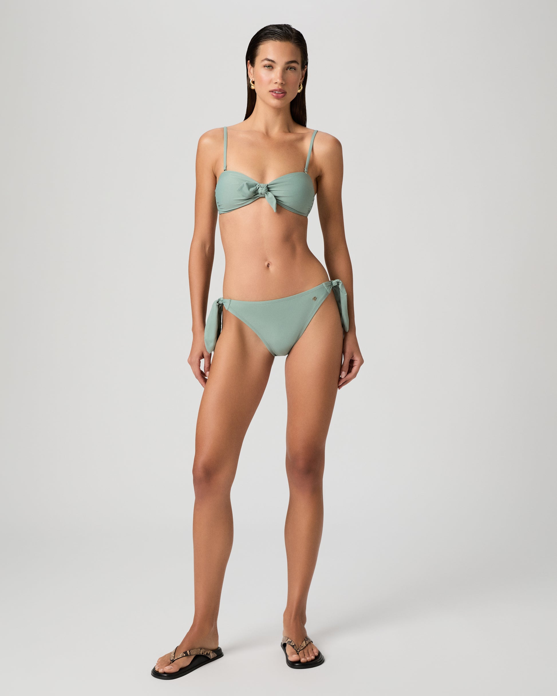 Woman wearing a light green bikini against a plain background