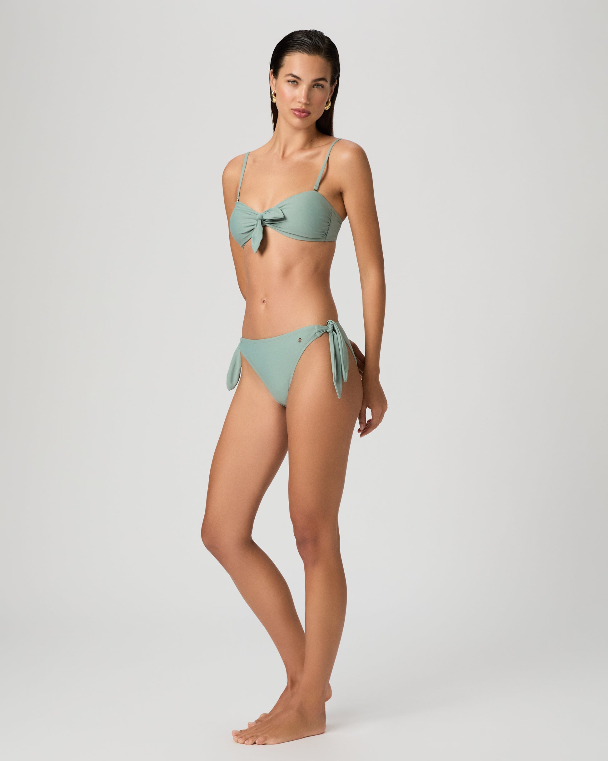 Woman wearing a light green bikini against a plain background