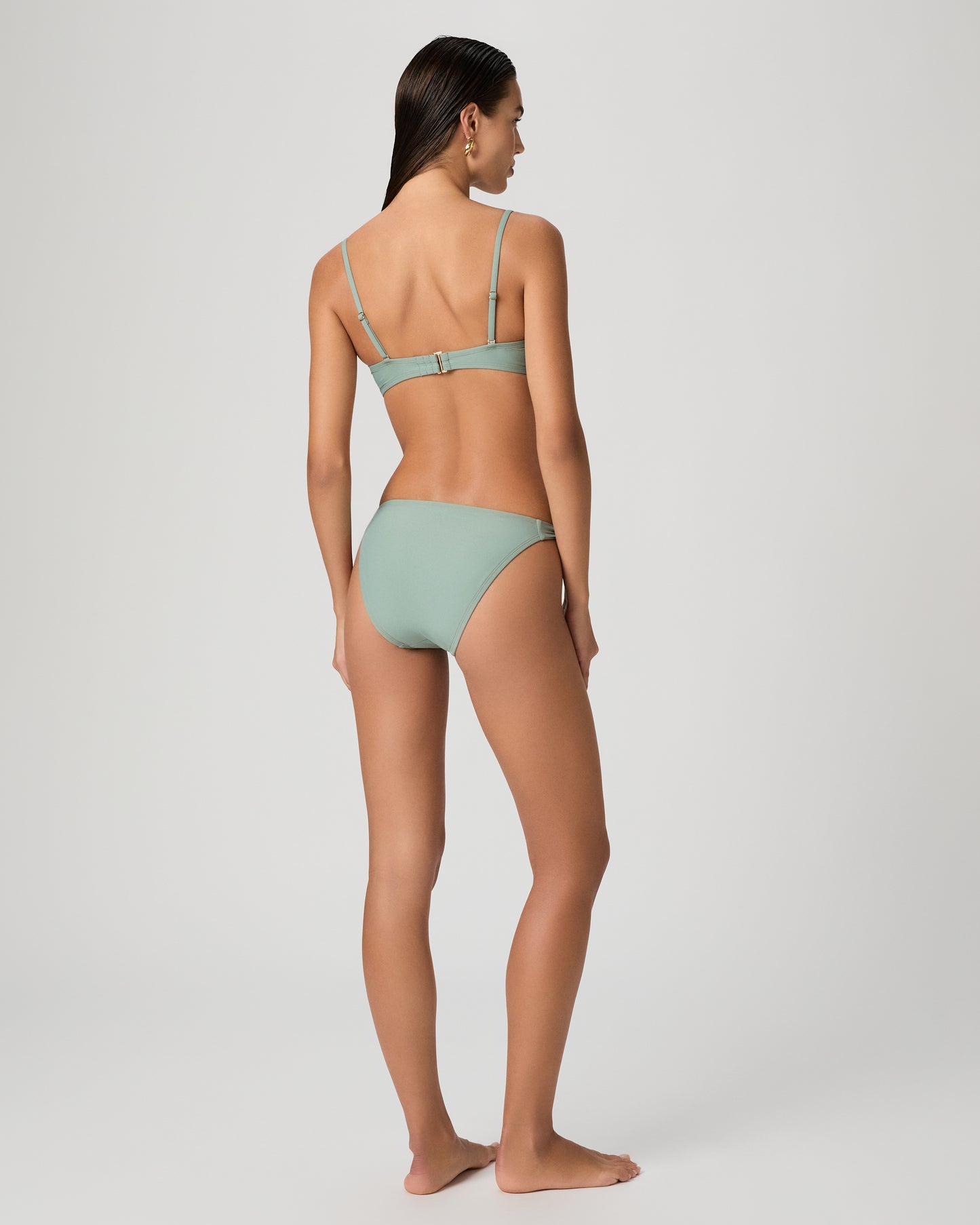 Woman wearing a light green bikini against a plain background