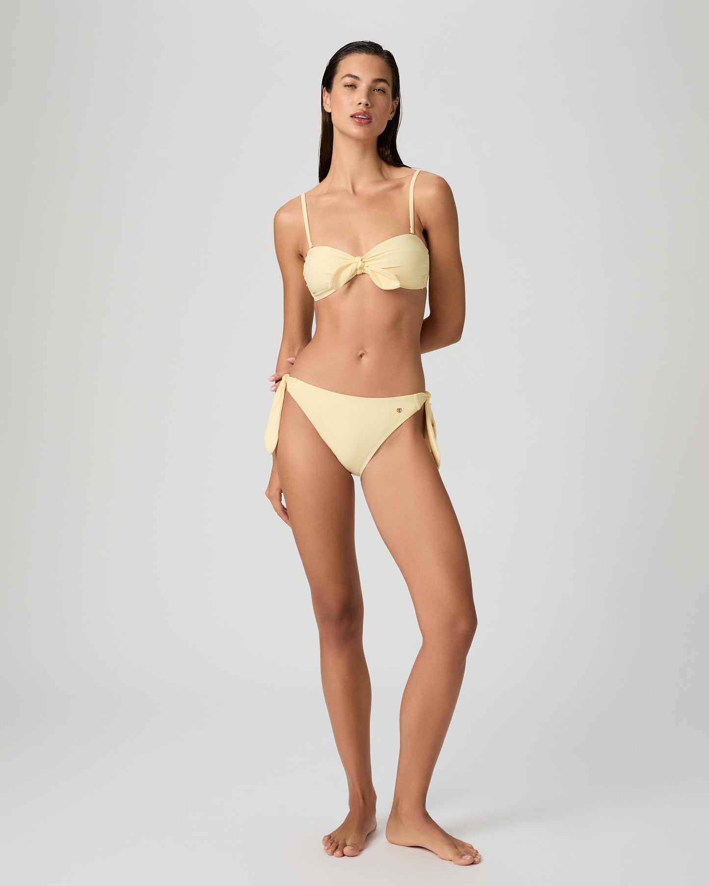 Woman wearing a yellow bikini against a plain background