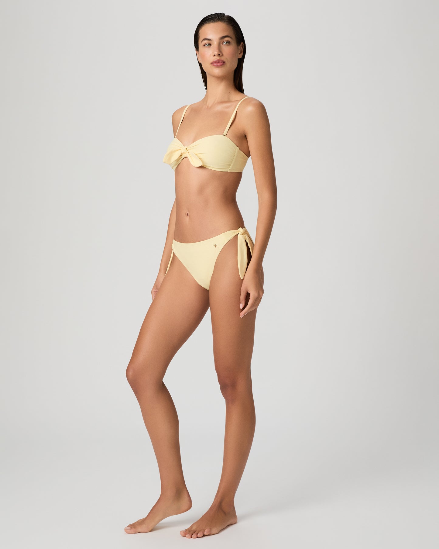 Woman wearing a yellow bikini against a plain background