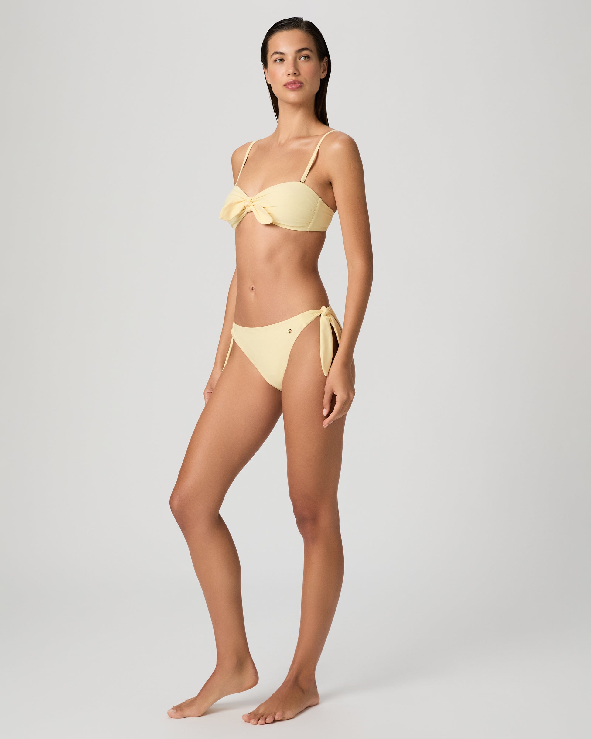 Woman wearing a yellow bikini against a plain background