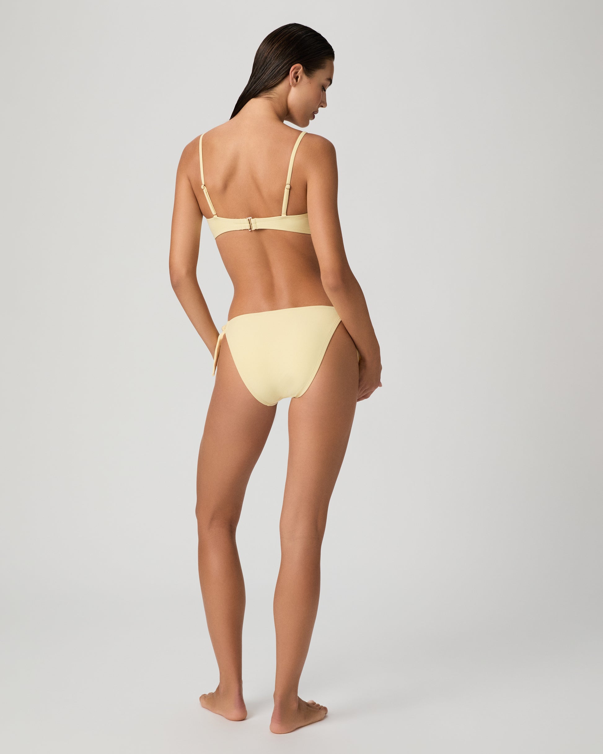 Woman wearing a yellow bikini against a plain background