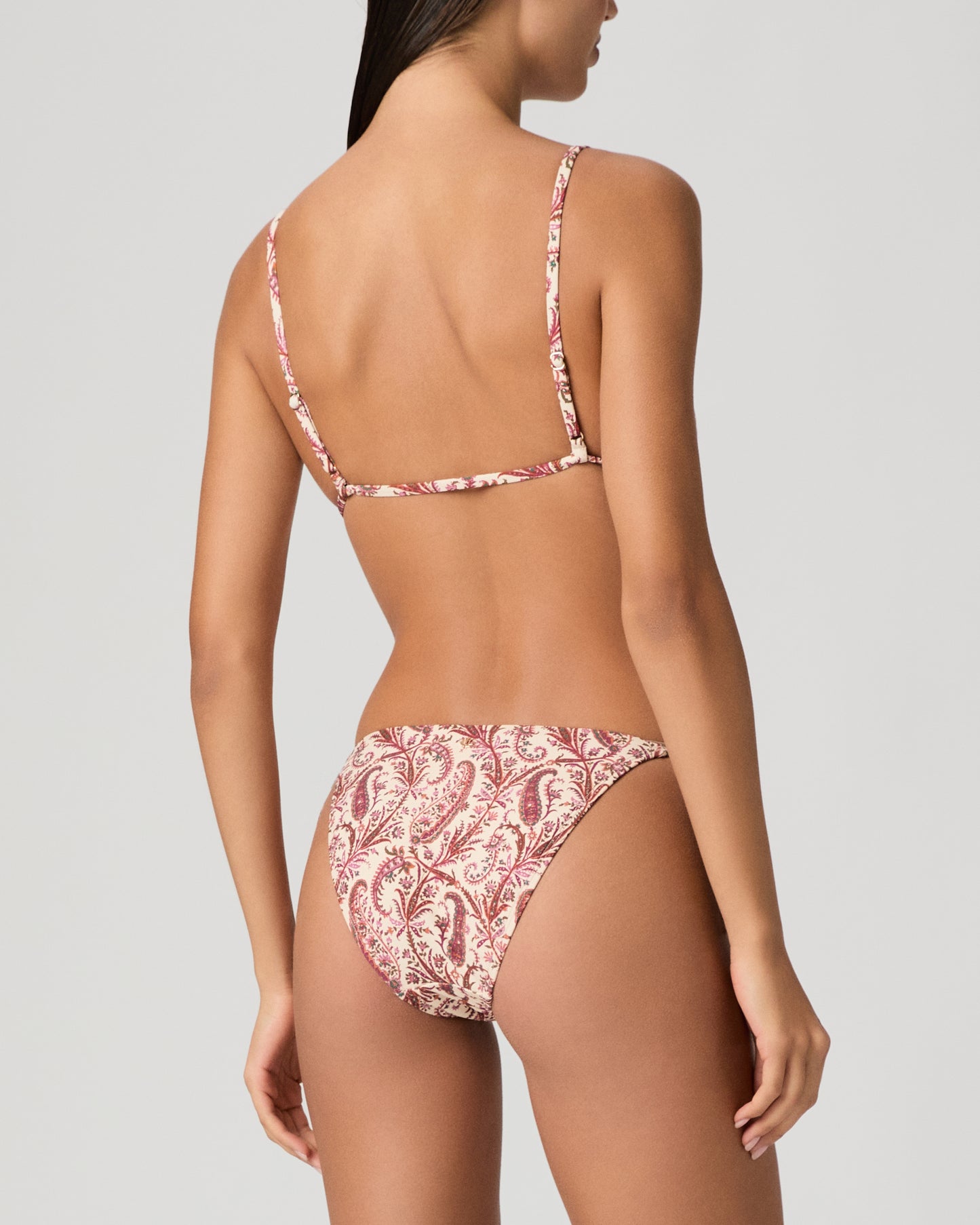 Woman wearing a red and white patterned bikini on a gray background