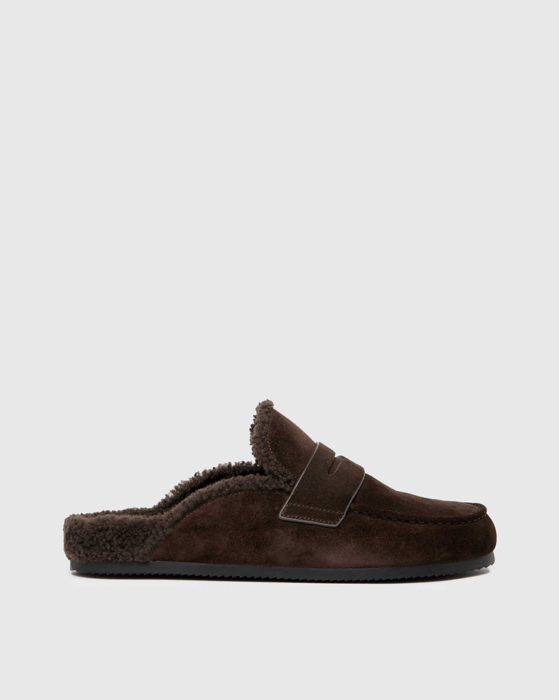 Chocolate color slipper with shearling lining on a light gray background