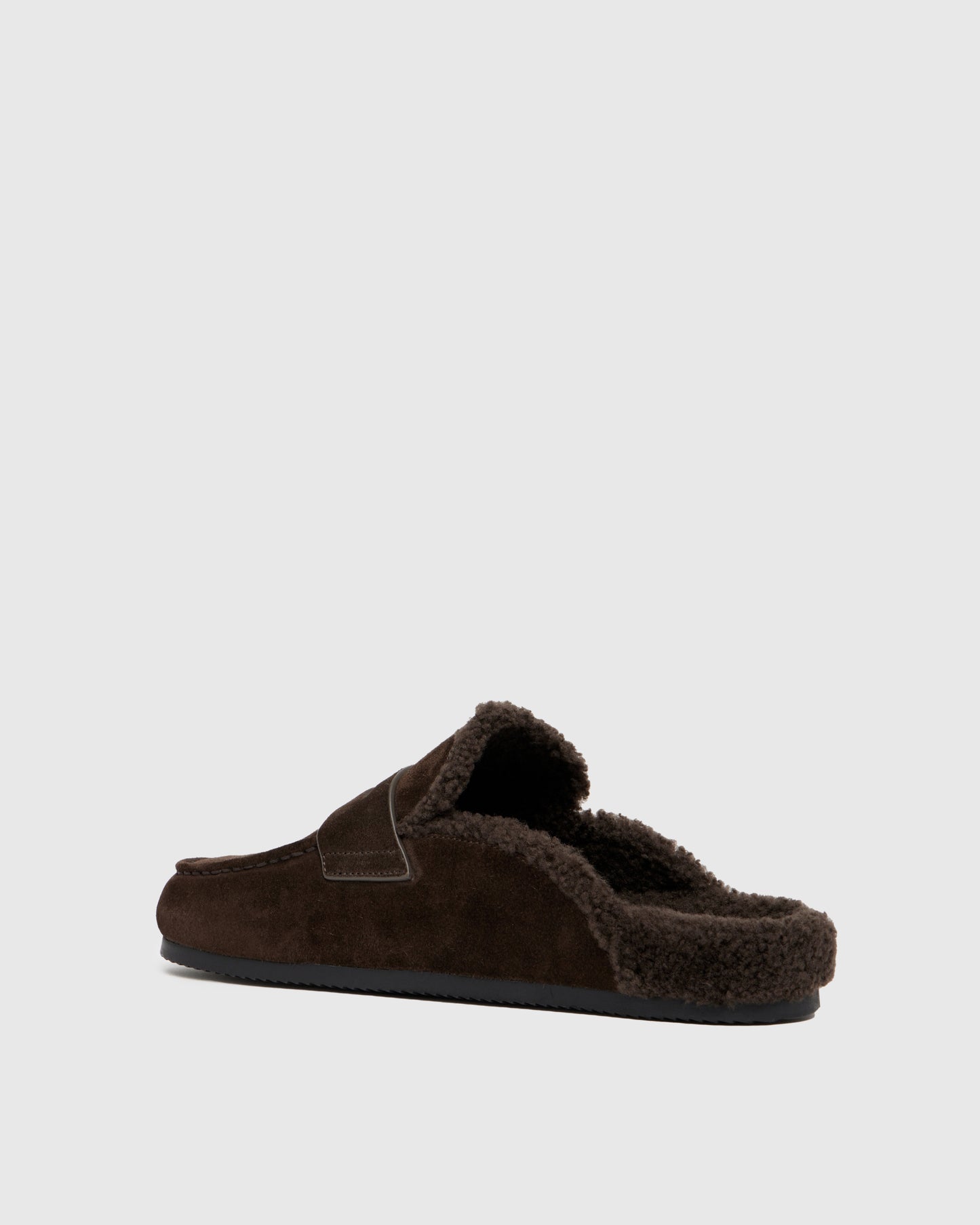 Chocolate color slipper with shearling lining on a light gray background