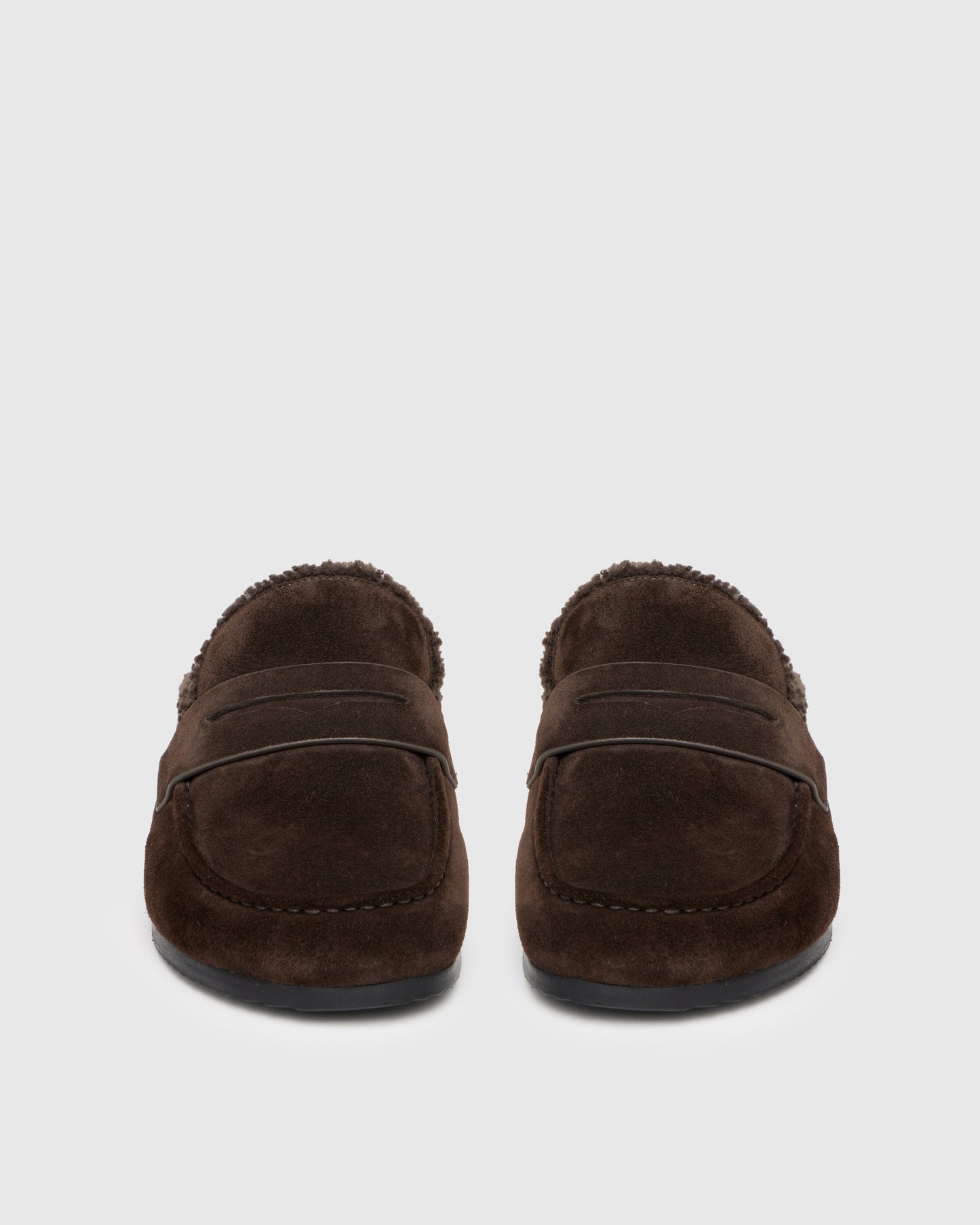 Chocolate color slipper with shearling lining on a light gray background