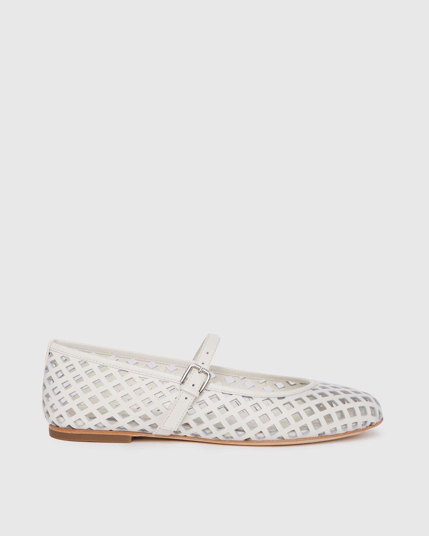 White flat shoe with a strap on a light gray background