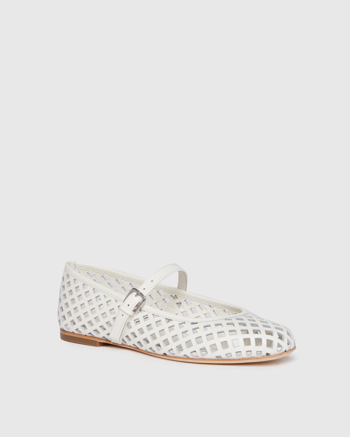 White flat shoe with a strap on a light gray background