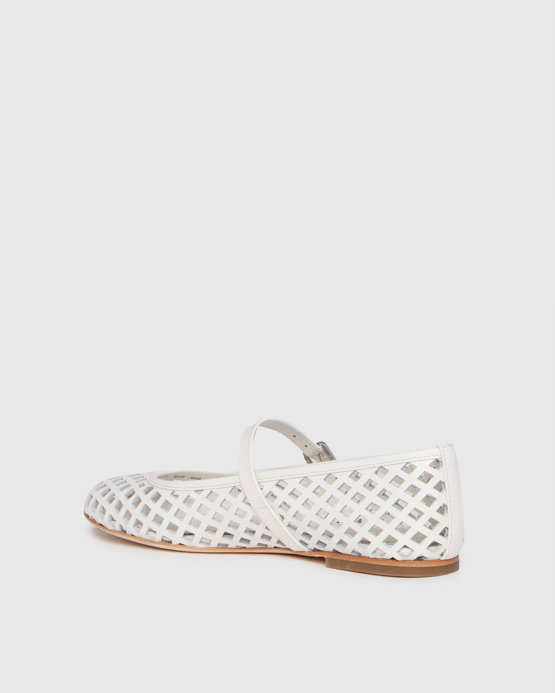 White flat shoe with a strap on a light gray background