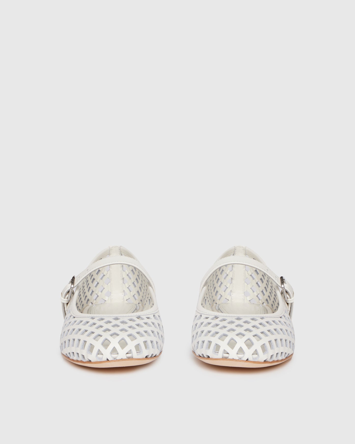 White flat shoe with a strap on a light gray background
