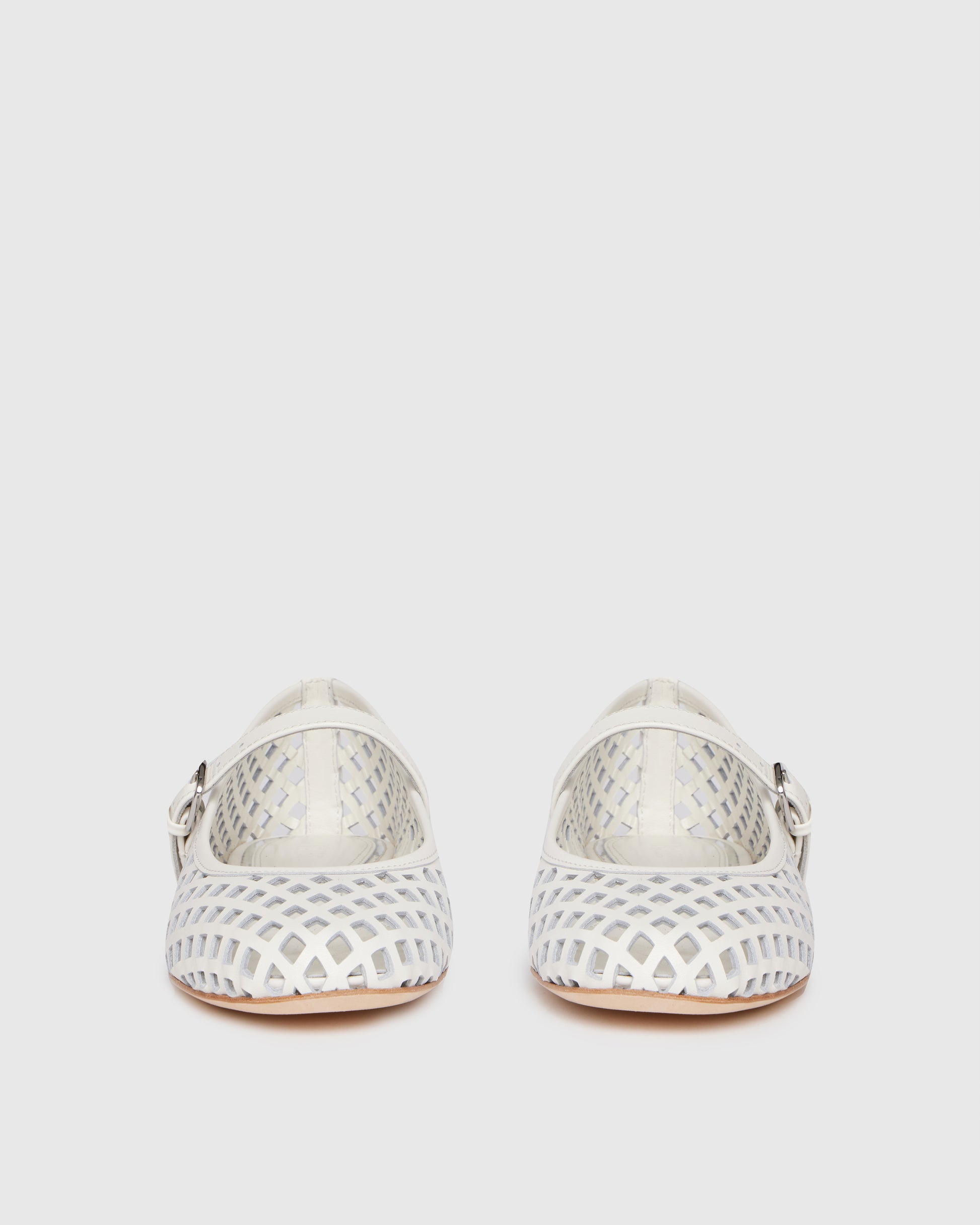 White flat shoe with a strap on a light gray background