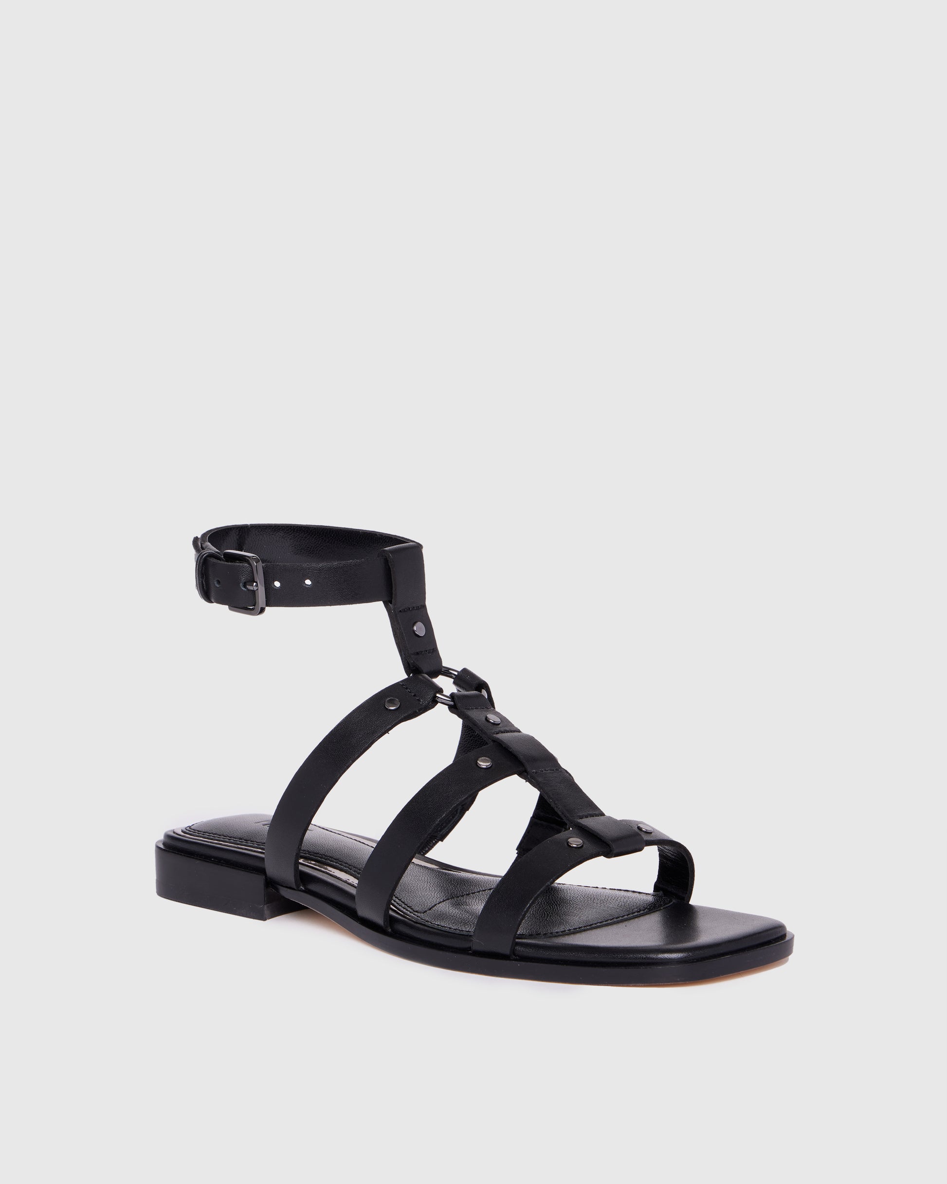 Black sandal with multiple straps on a light gray background