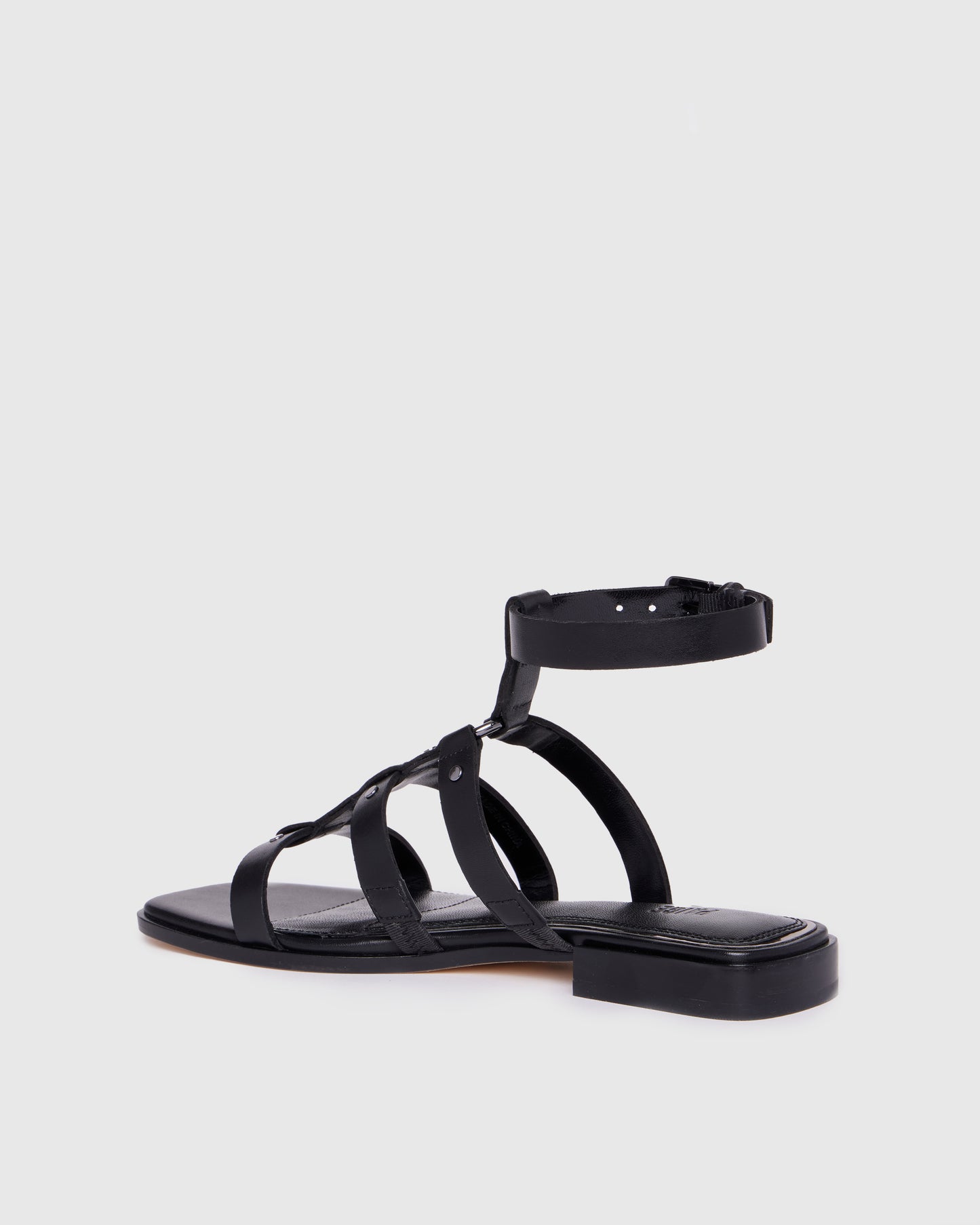 Black sandal with thin straps on a light gray background