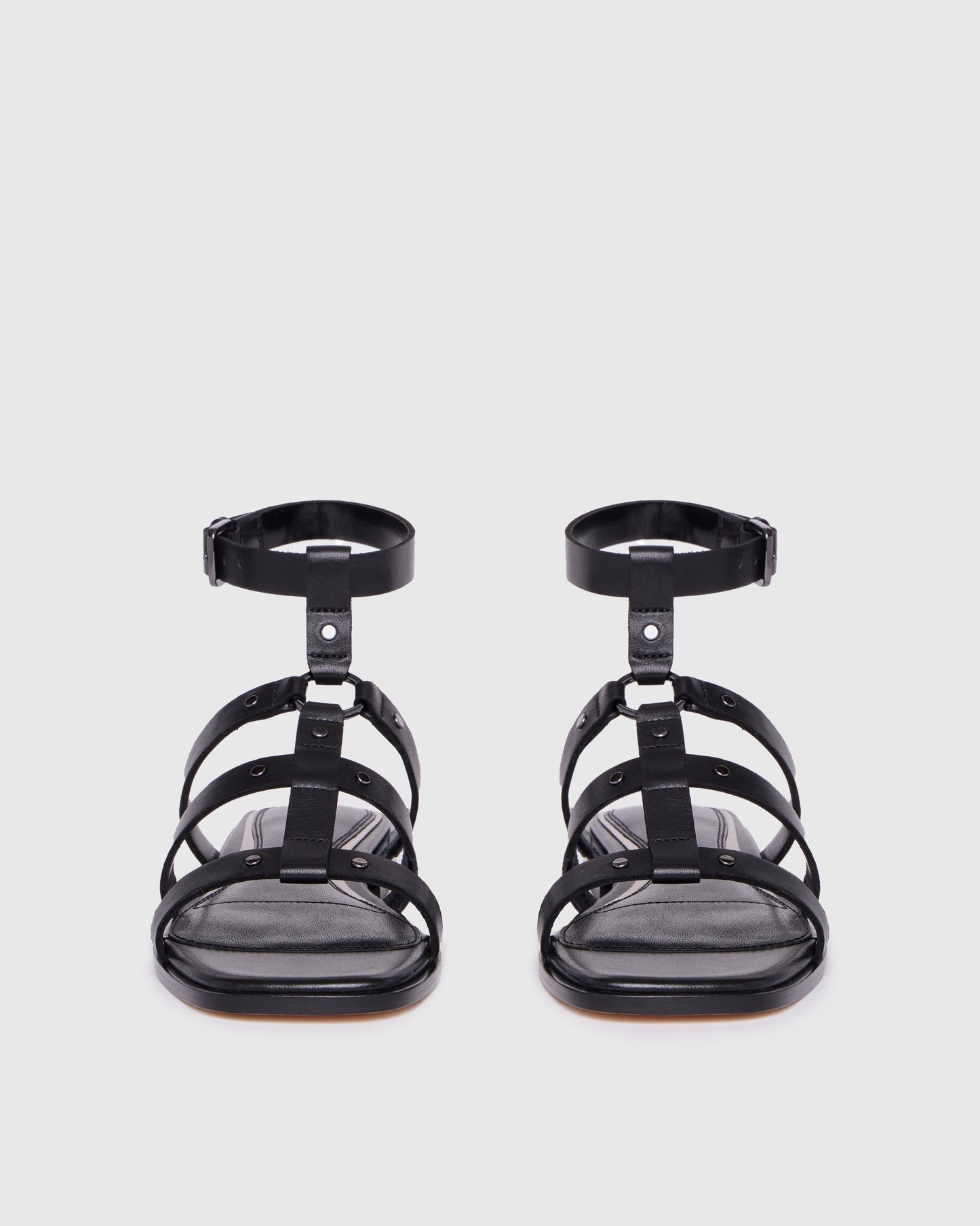 Black strappy sandals on a light gray background