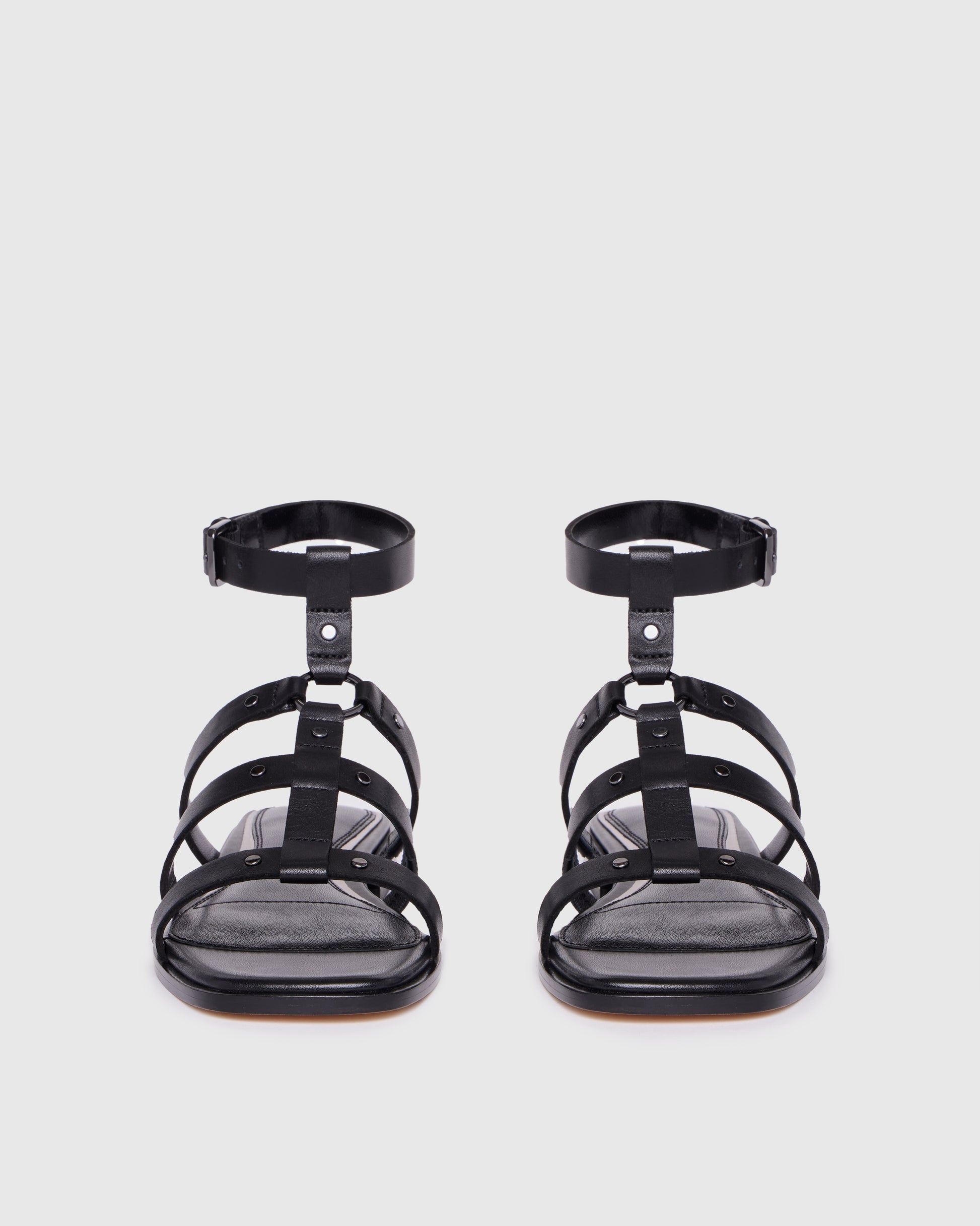 Black strappy sandals on a light gray background
