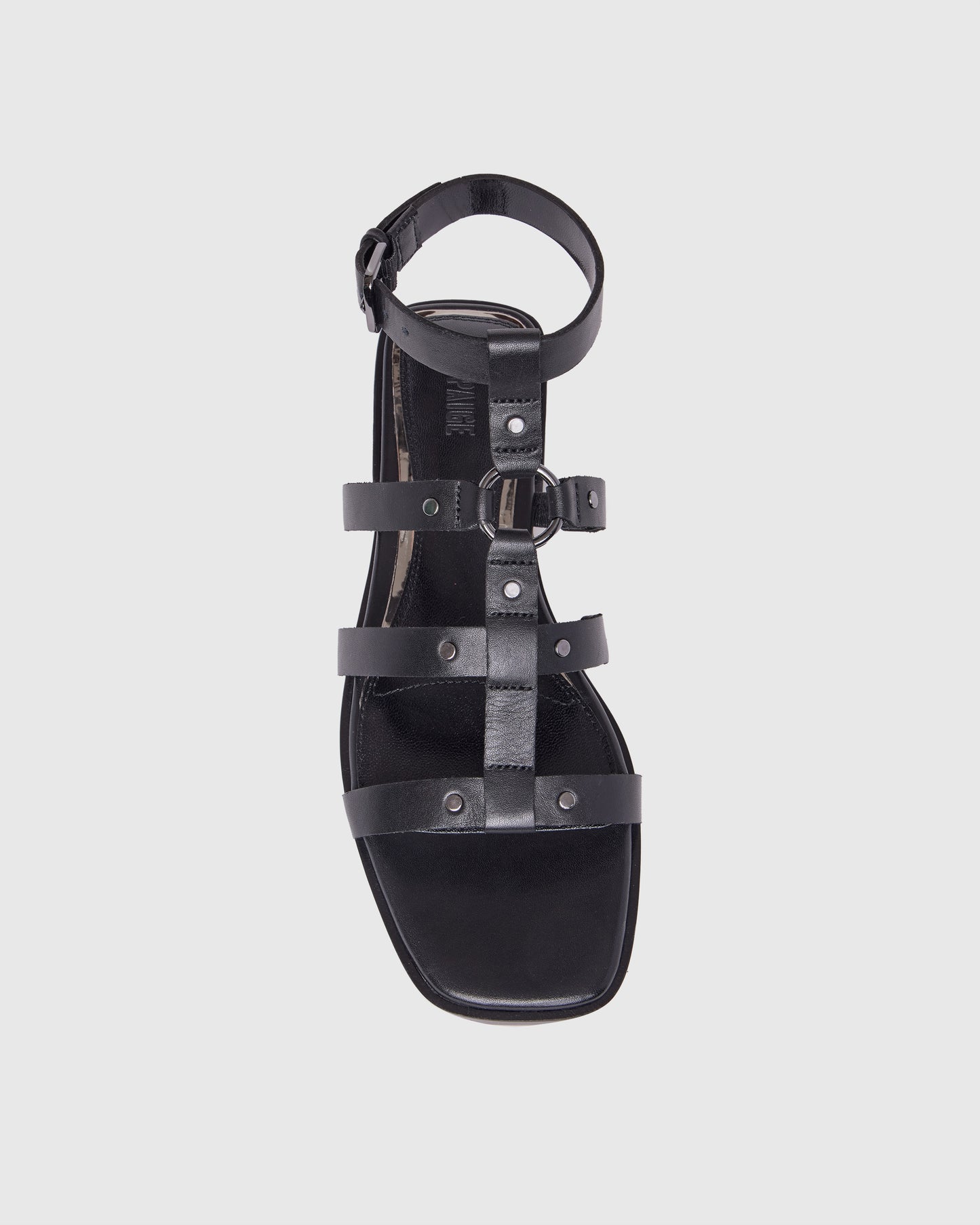 Black leather shoe with studded details on a light gray background
