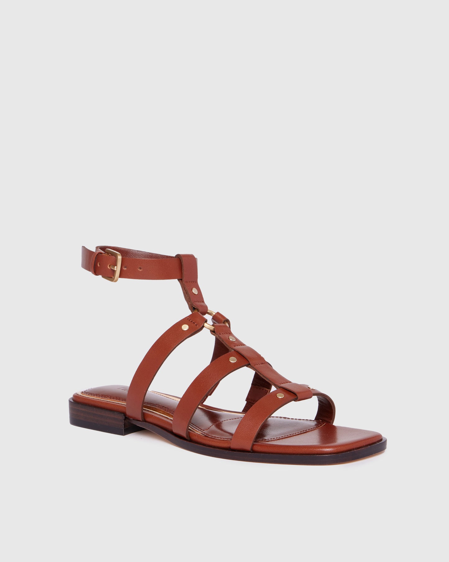 Brown leather sandal with thin straps on a light gray background