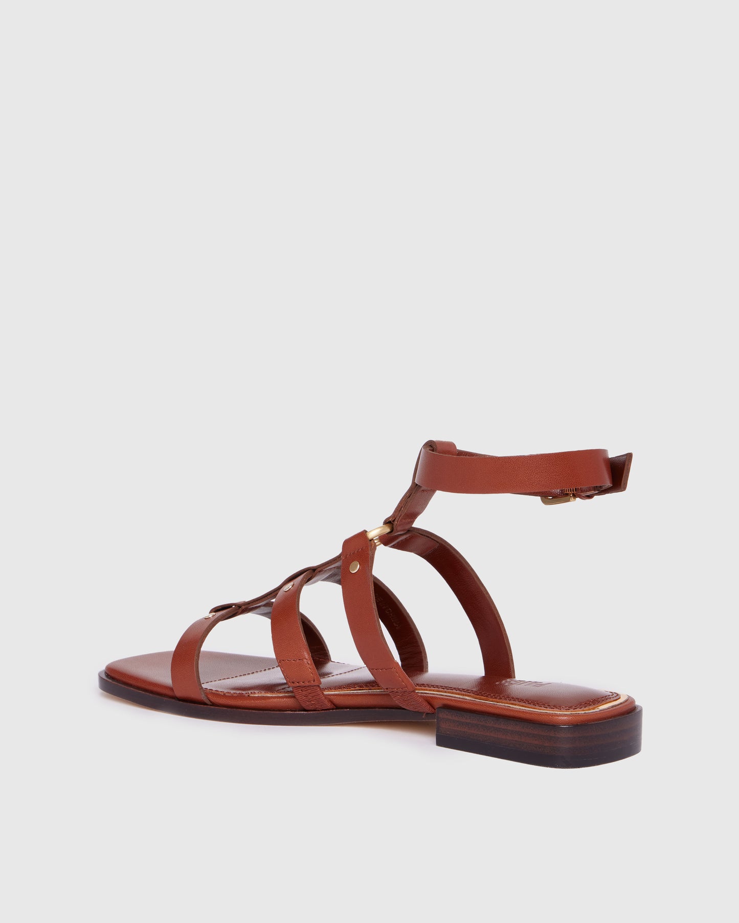 Brown leather sandal with thin straps on a light gray background