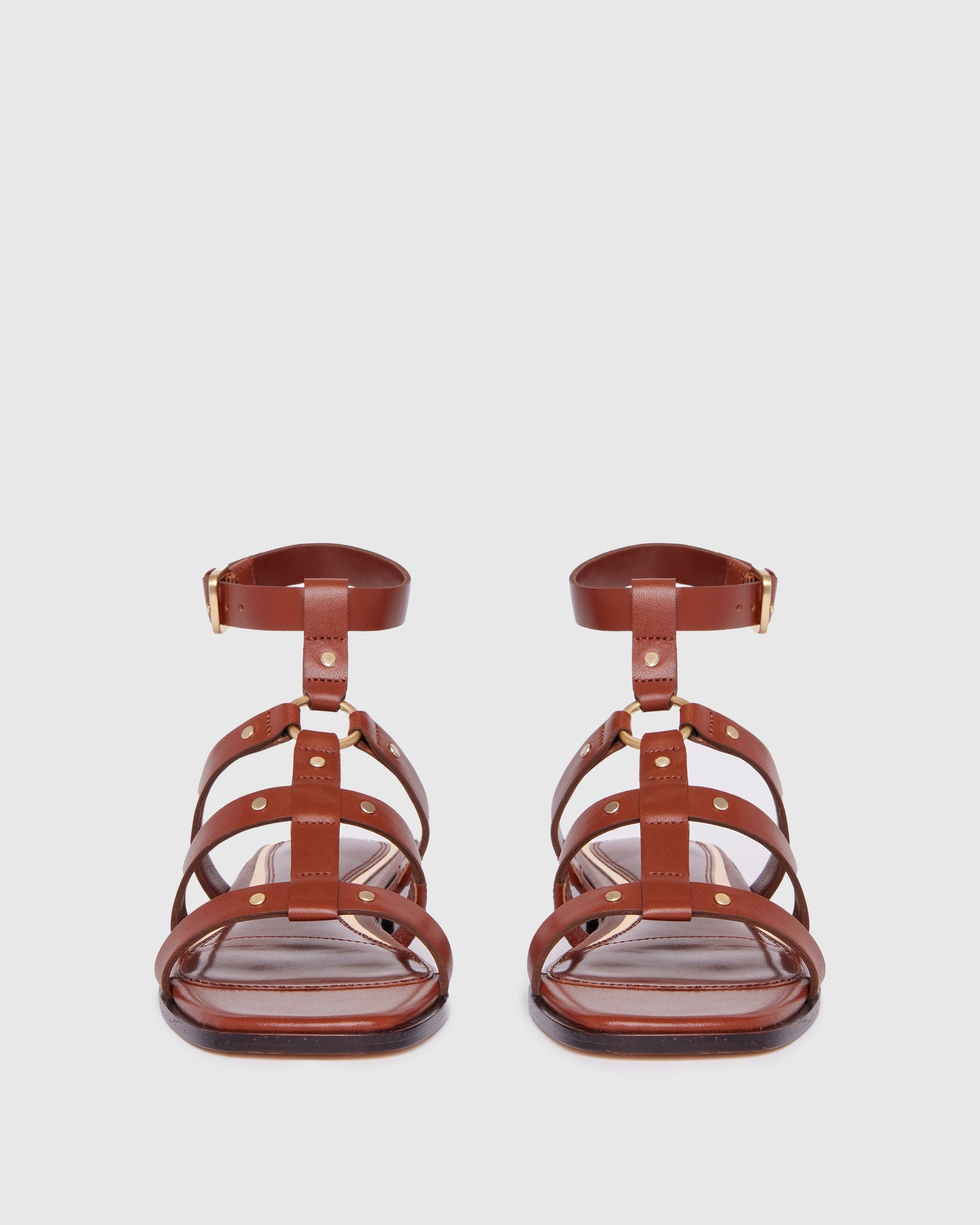 Brown leather sandal with thin straps on a light gray background
