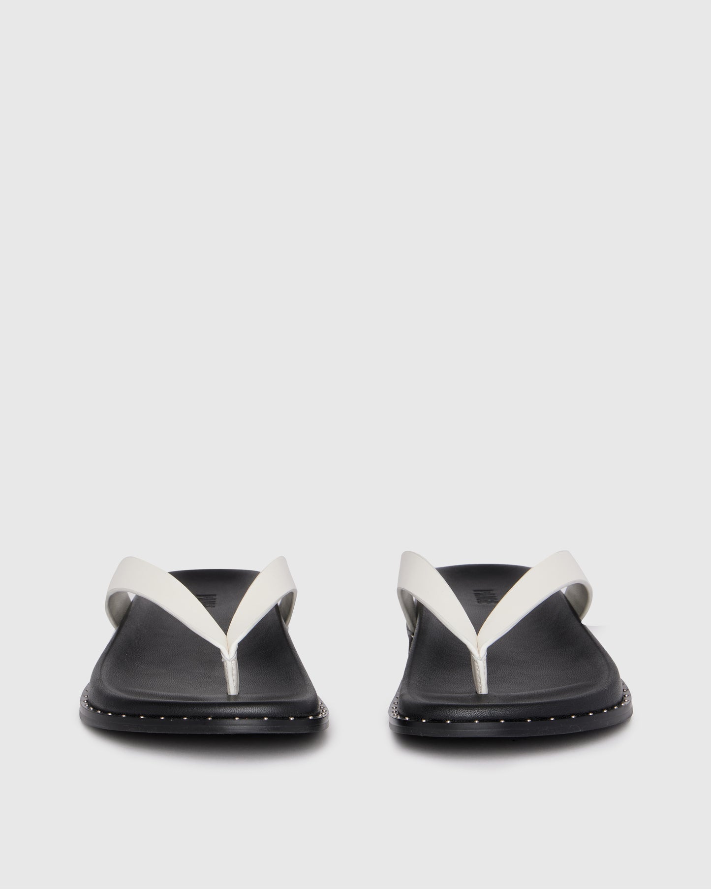Pair of black sandals with white straps on a light gray background