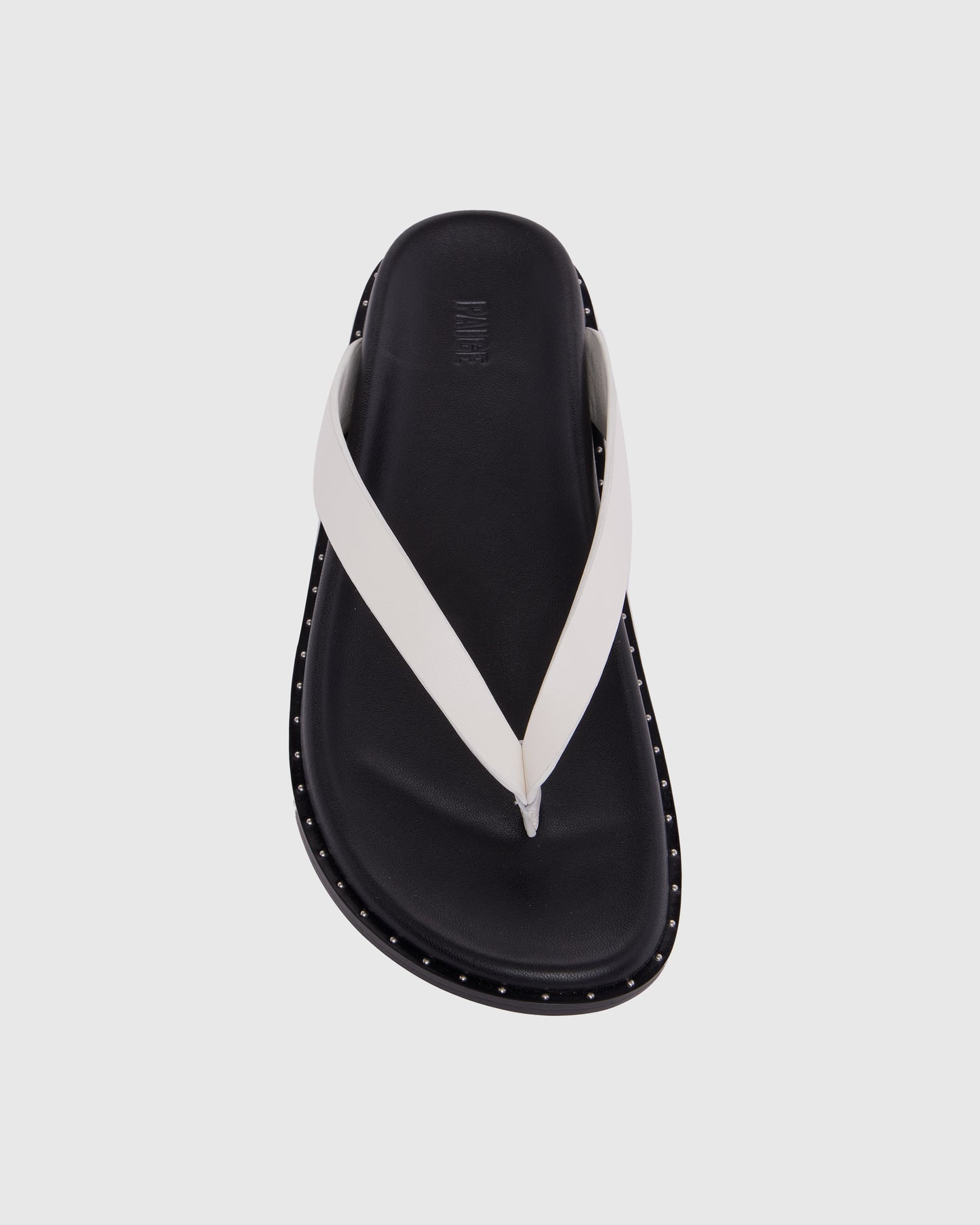 Black sandal with white strap on a light gray background