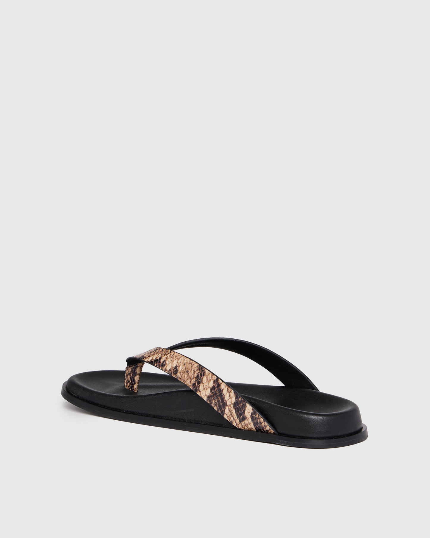 Black sandal with snake print strap on a light gray background