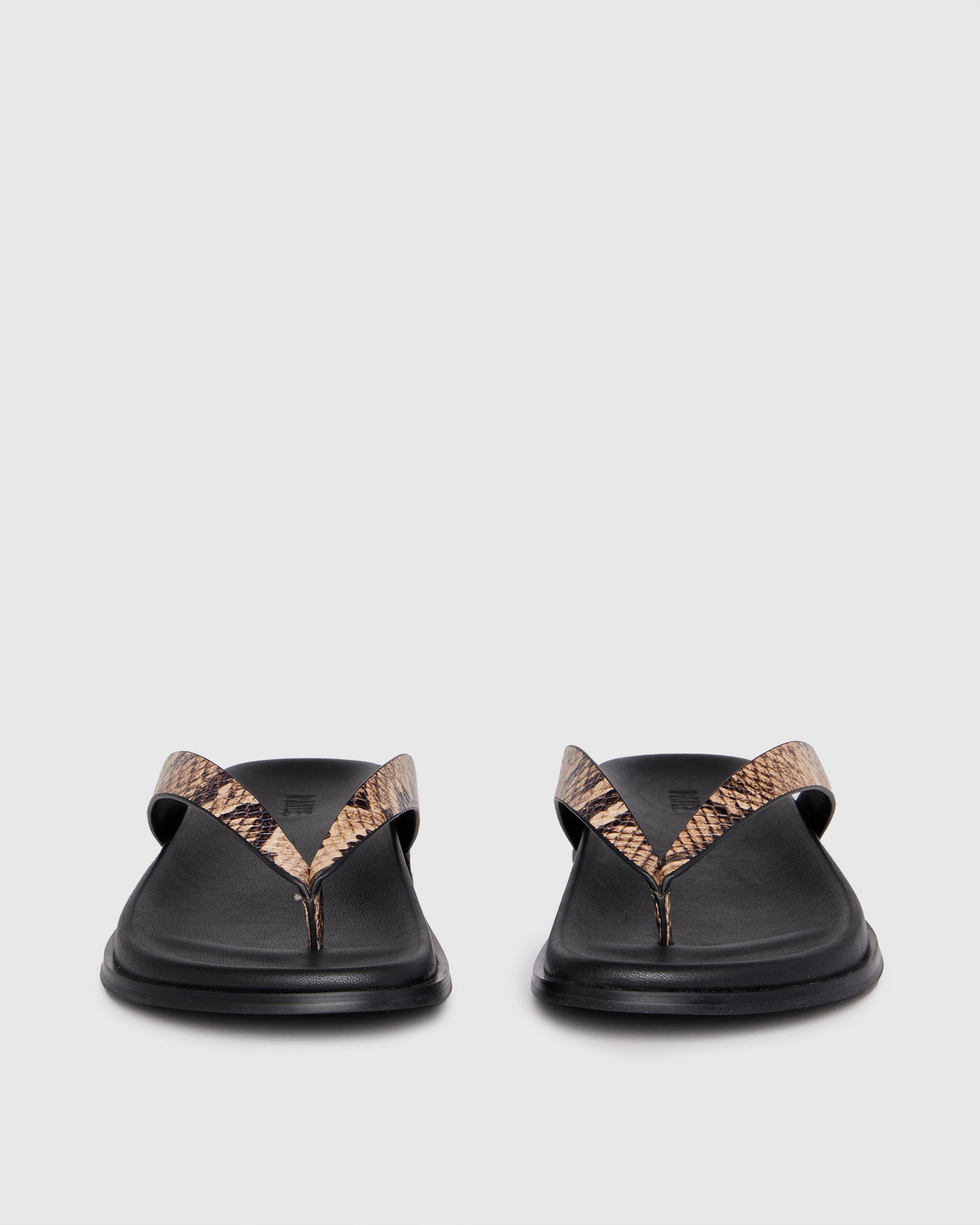 Black sandal with snake print strap on a light gray background
