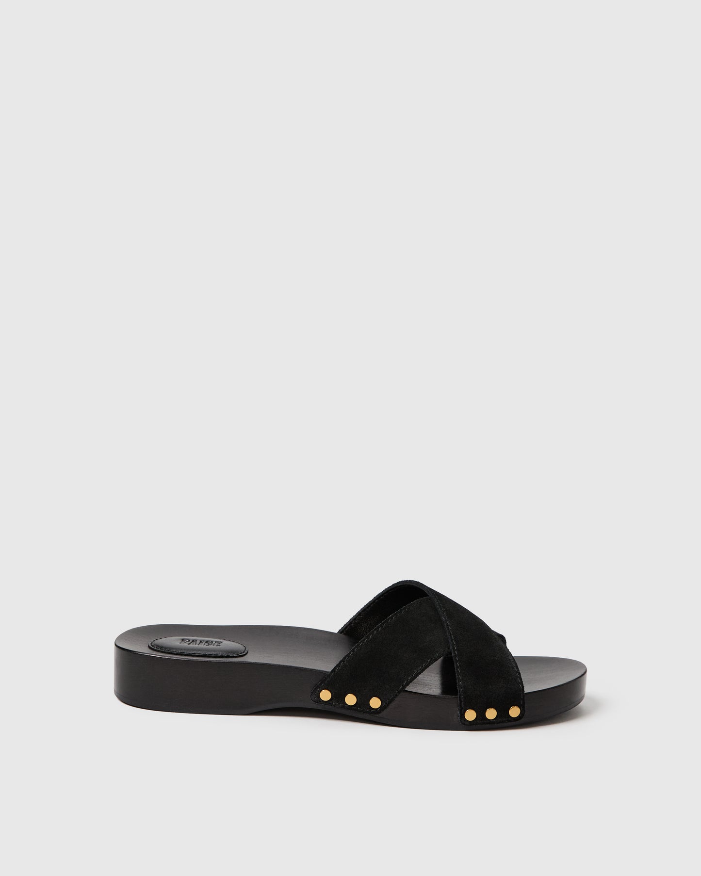 Black sandal with criss-cross straps on a light gray background