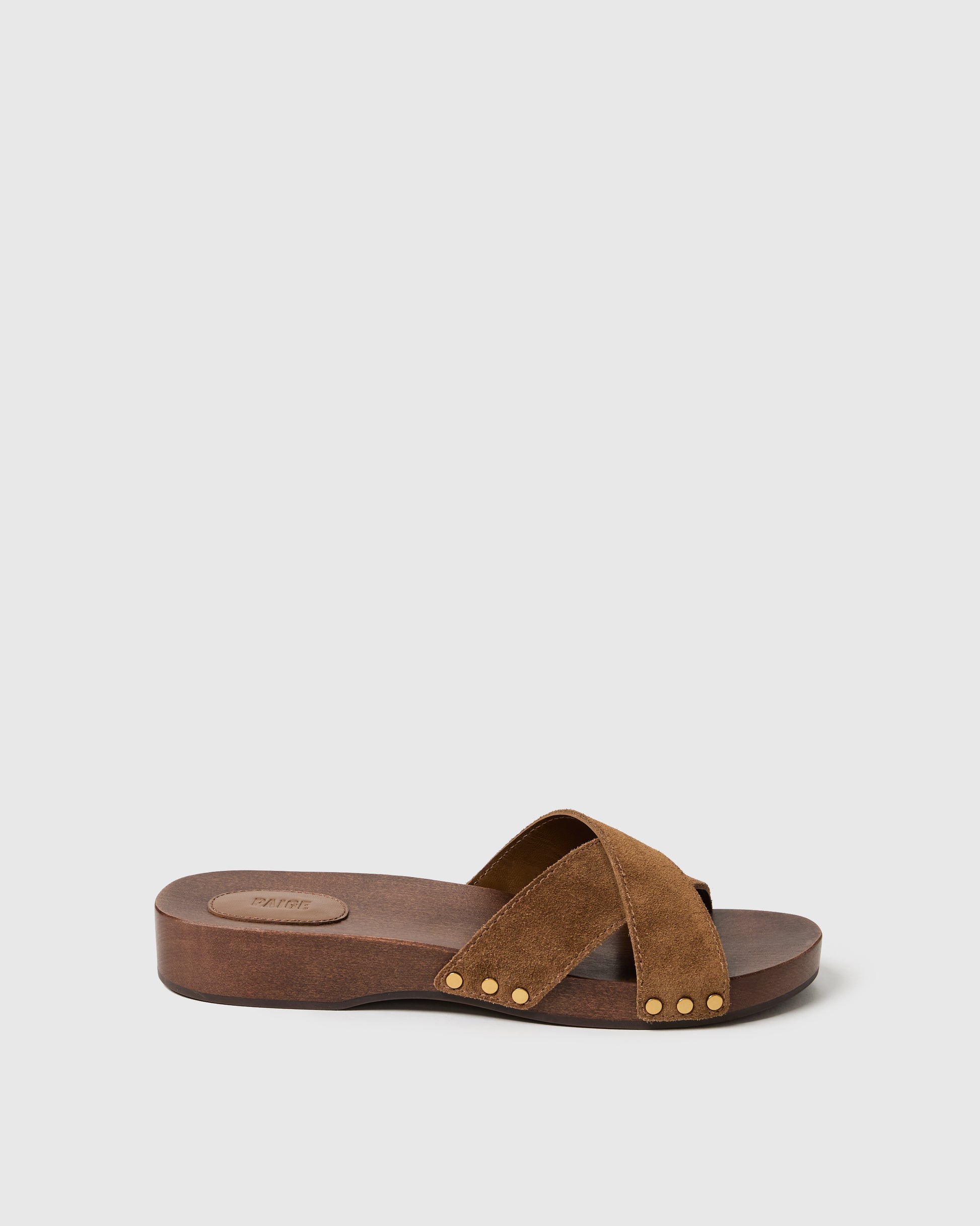 Brown sandal with gold studs on a light gray background