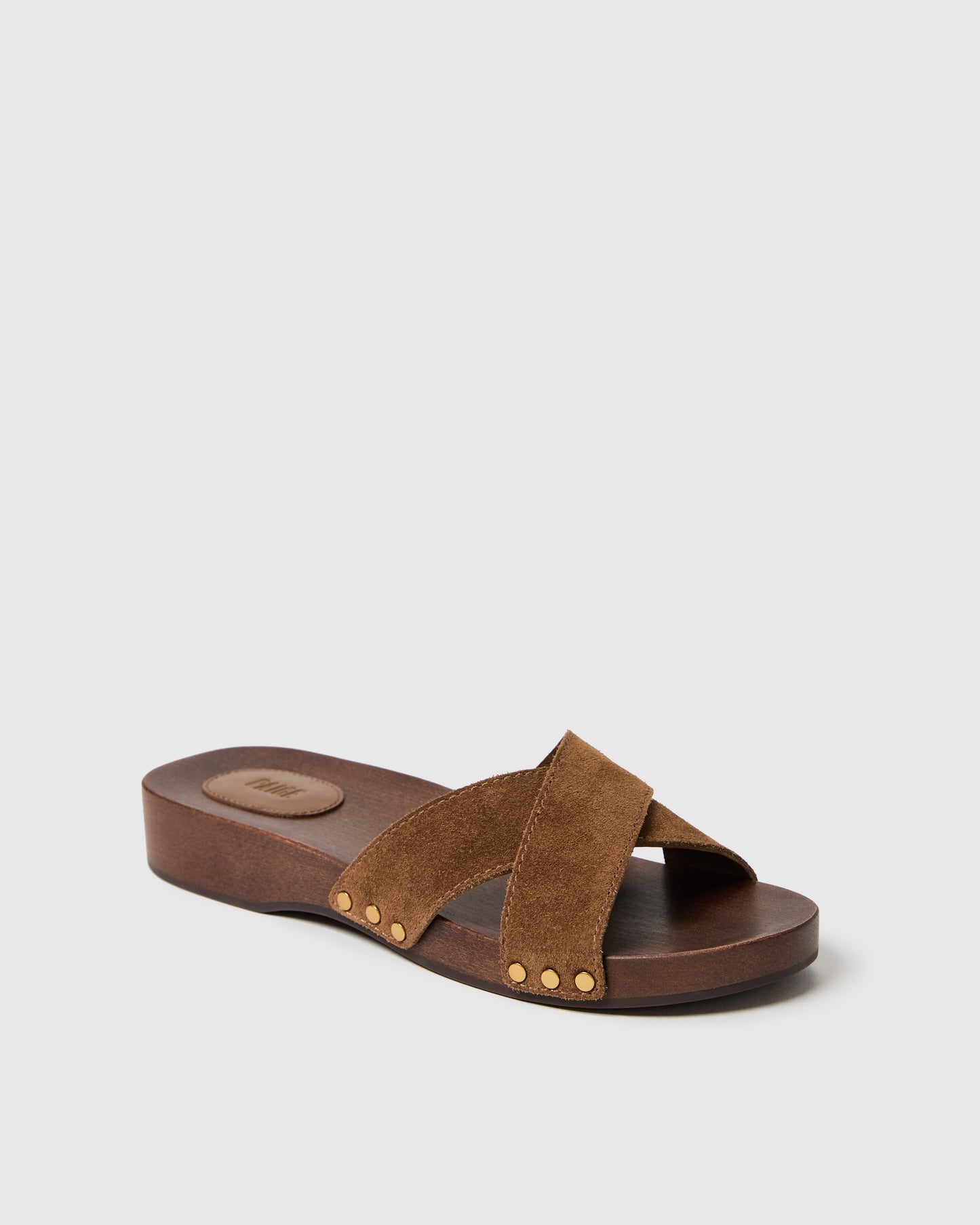 Brown sandal with criss-cross straps on a light gray background