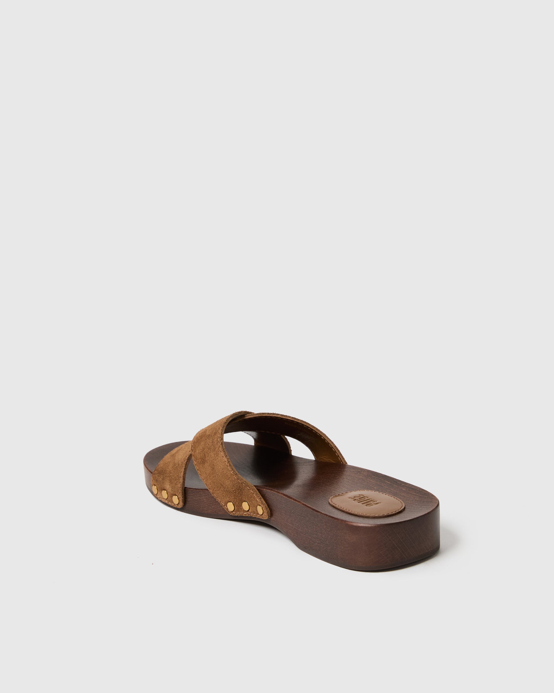 Brown sandal with criss-cross straps on a light gray background