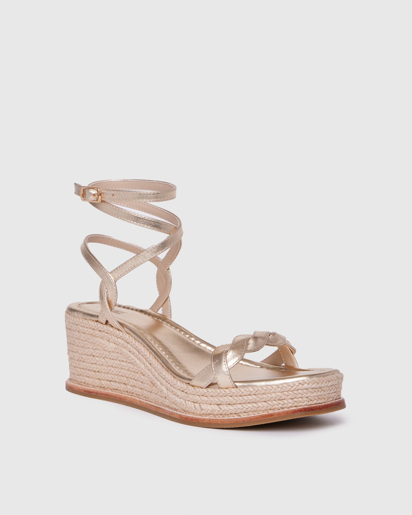 Gold wedge sandal with espadrille sole on a light gray background