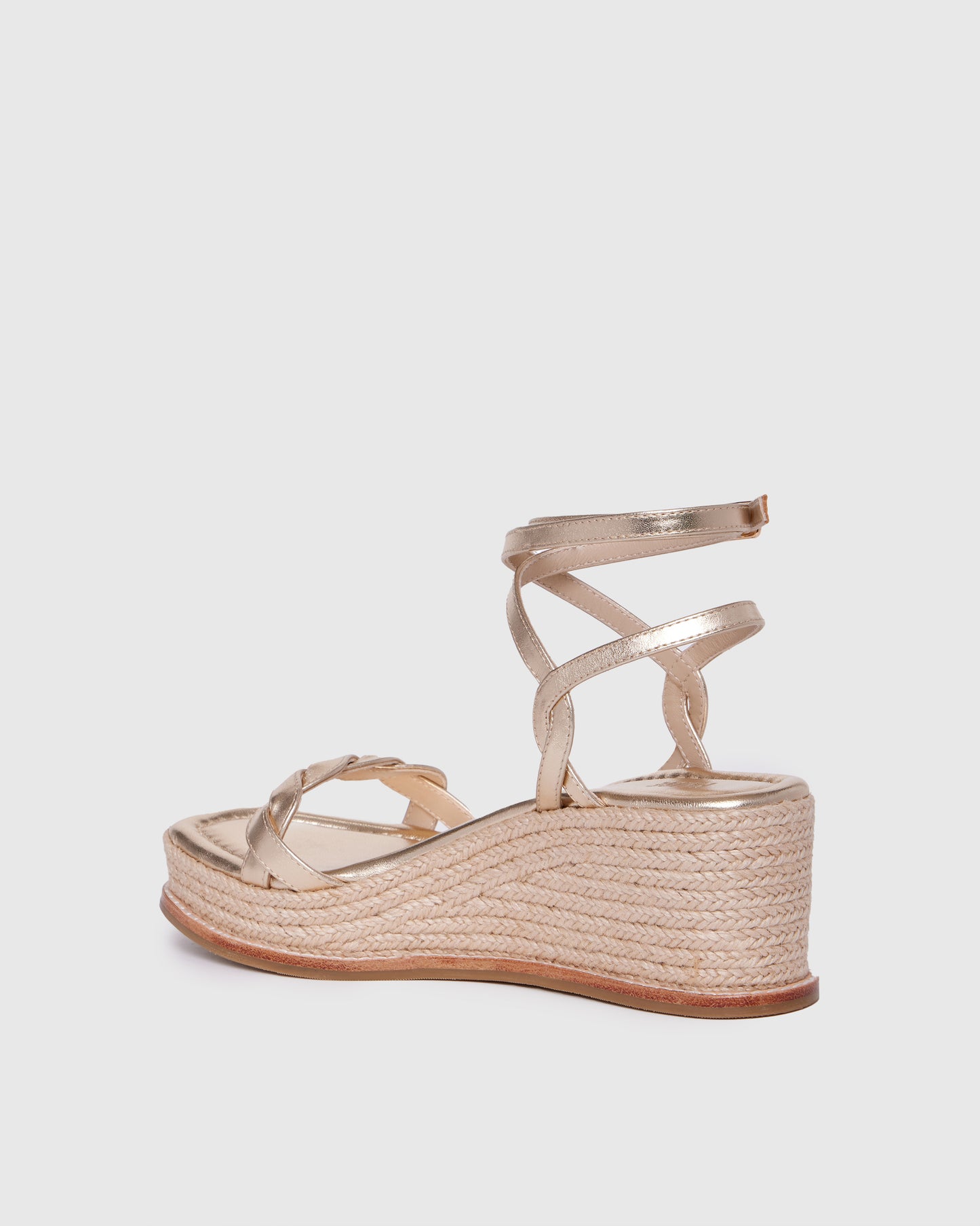Gold wedge sandal with espadrille sole on a light gray background