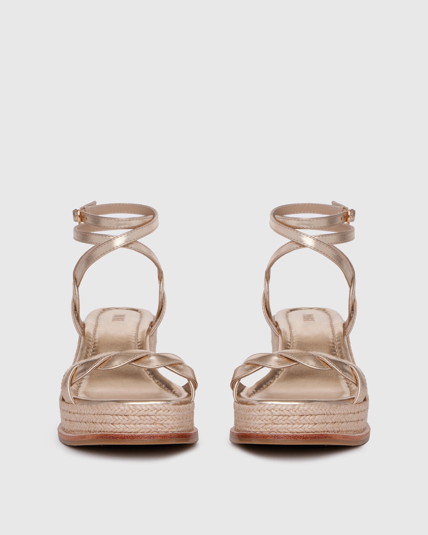 Gold wedge sandal with espadrille sole on a light gray background