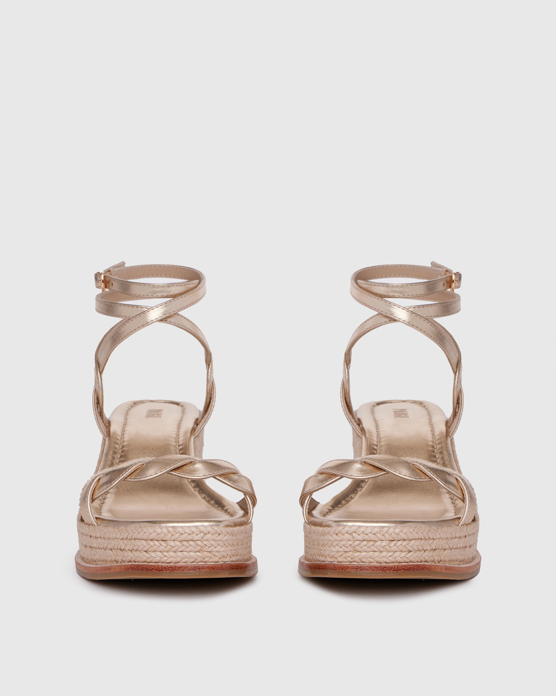 Gold wedge sandal with espadrille sole on a light gray background