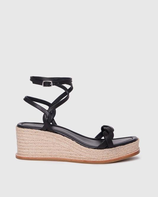 Black wedge sandal with espadrille sole on a light gray background