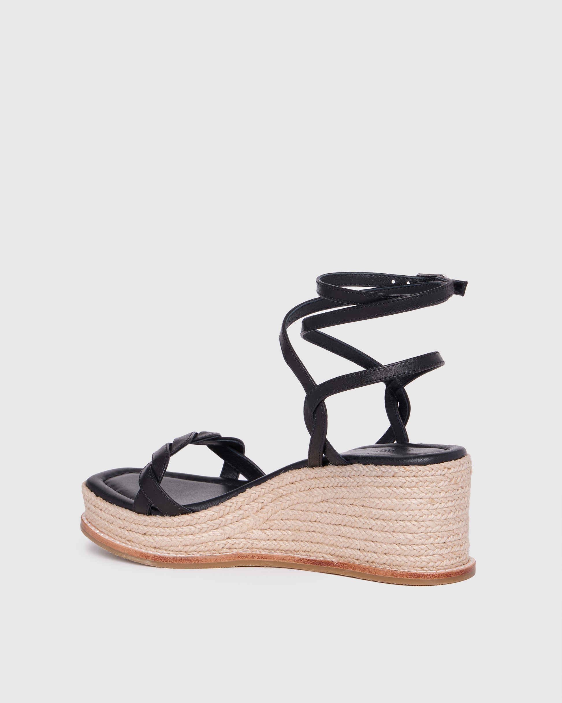 Black wedge sandal with espadrille sole on a light gray background