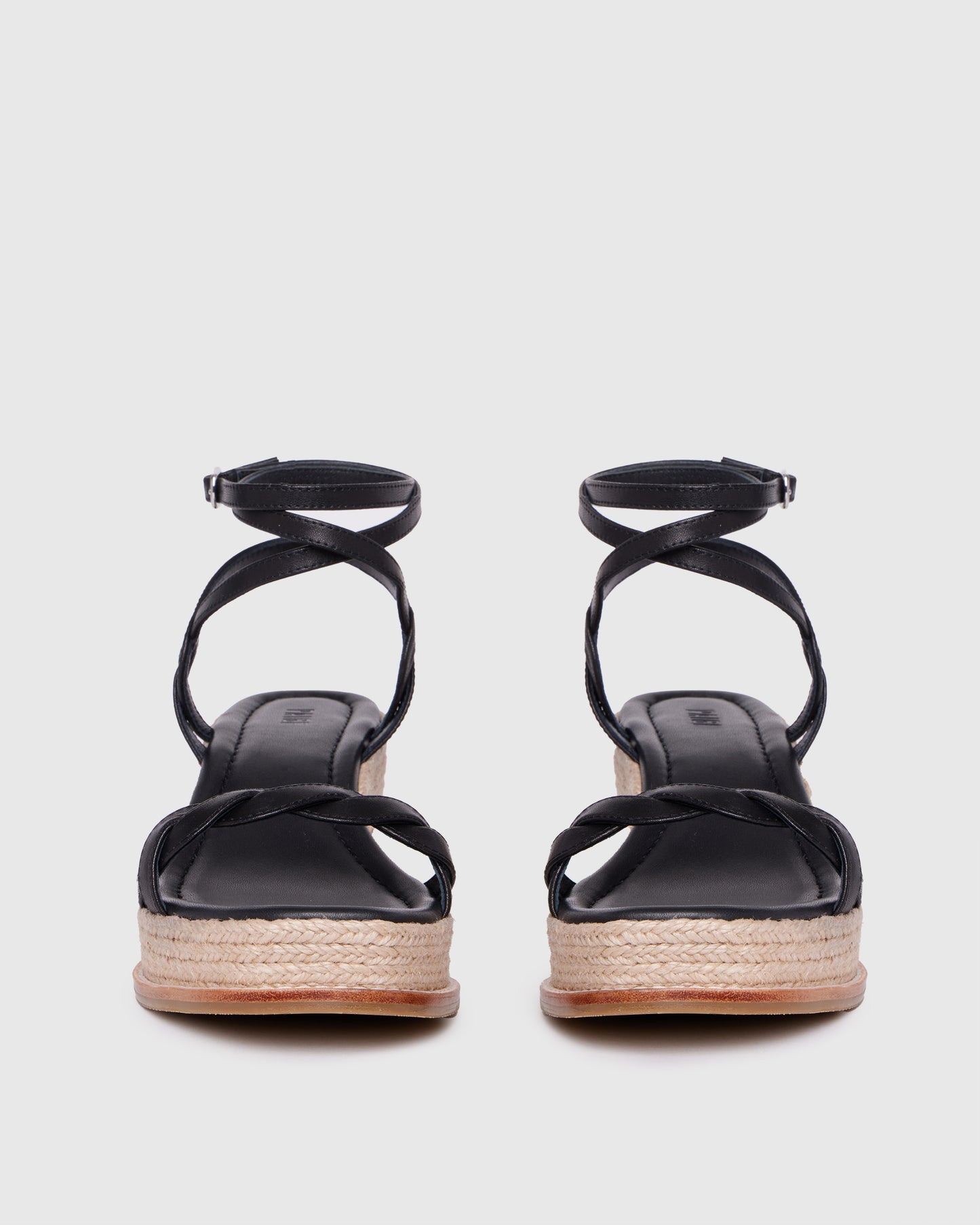 Black sandals with espadrille sole on a light gray background