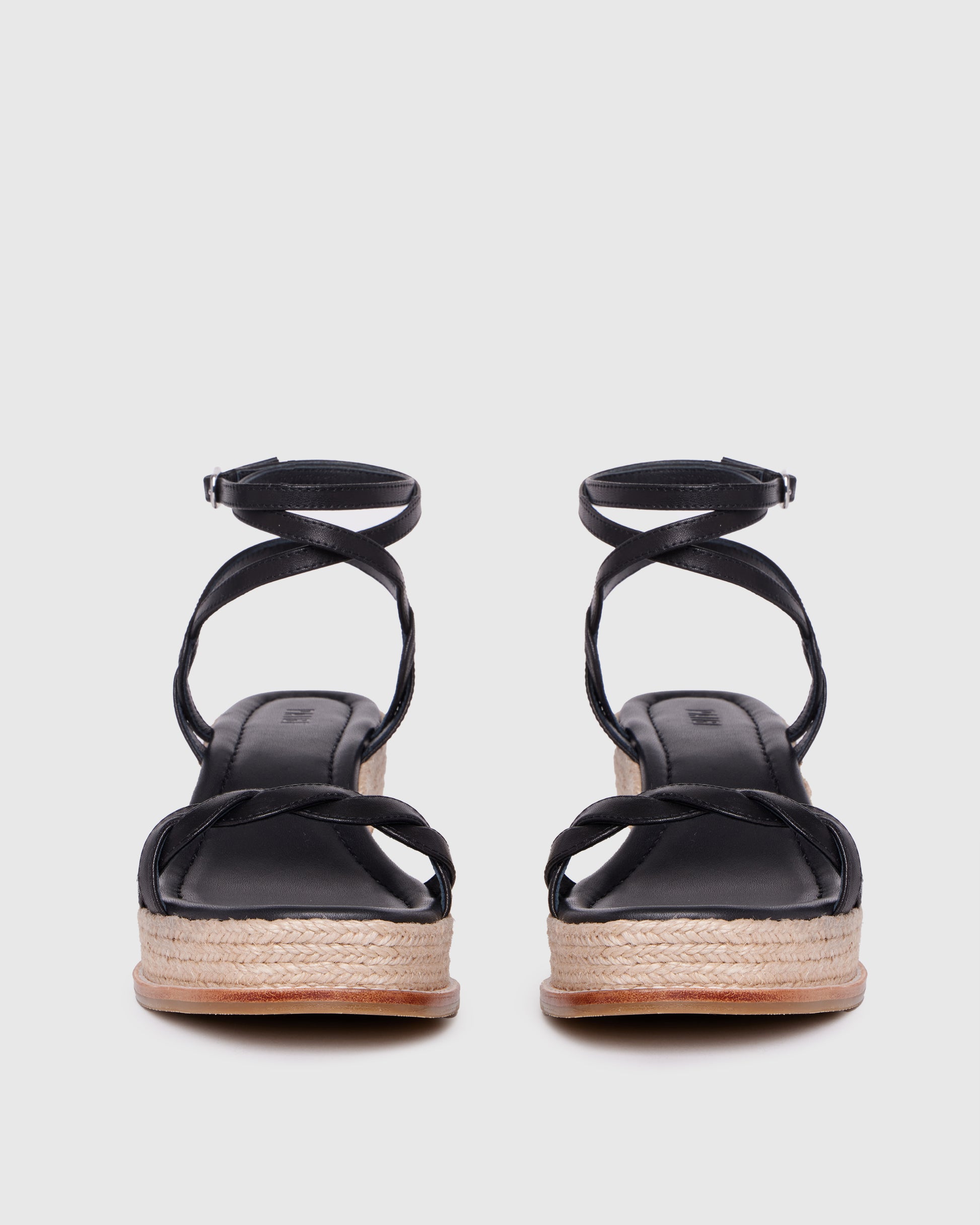 Black sandals with espadrille sole on a light gray background