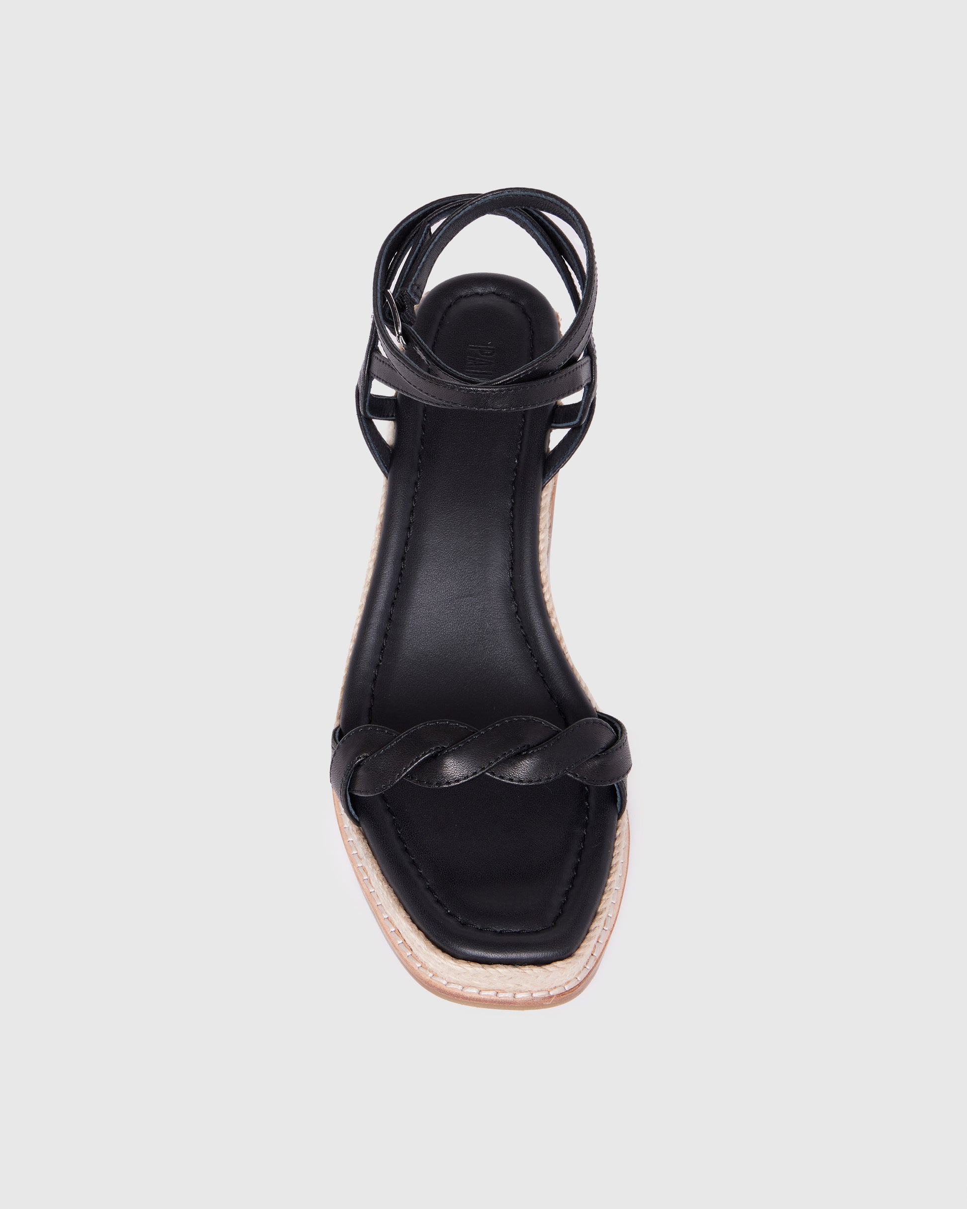 Black sandal with braided design on a light gray background