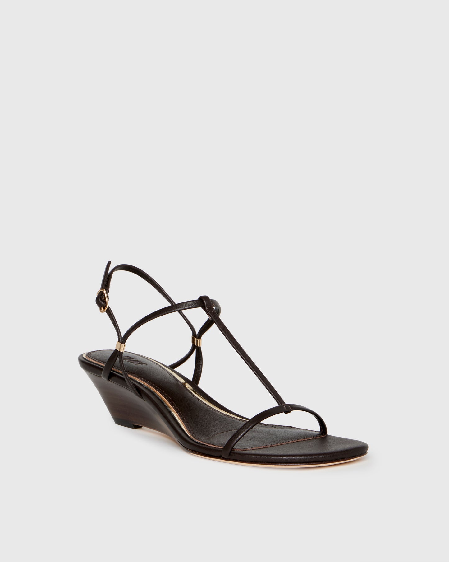 Chocolate wedge sandal with thin straps on a light gray background