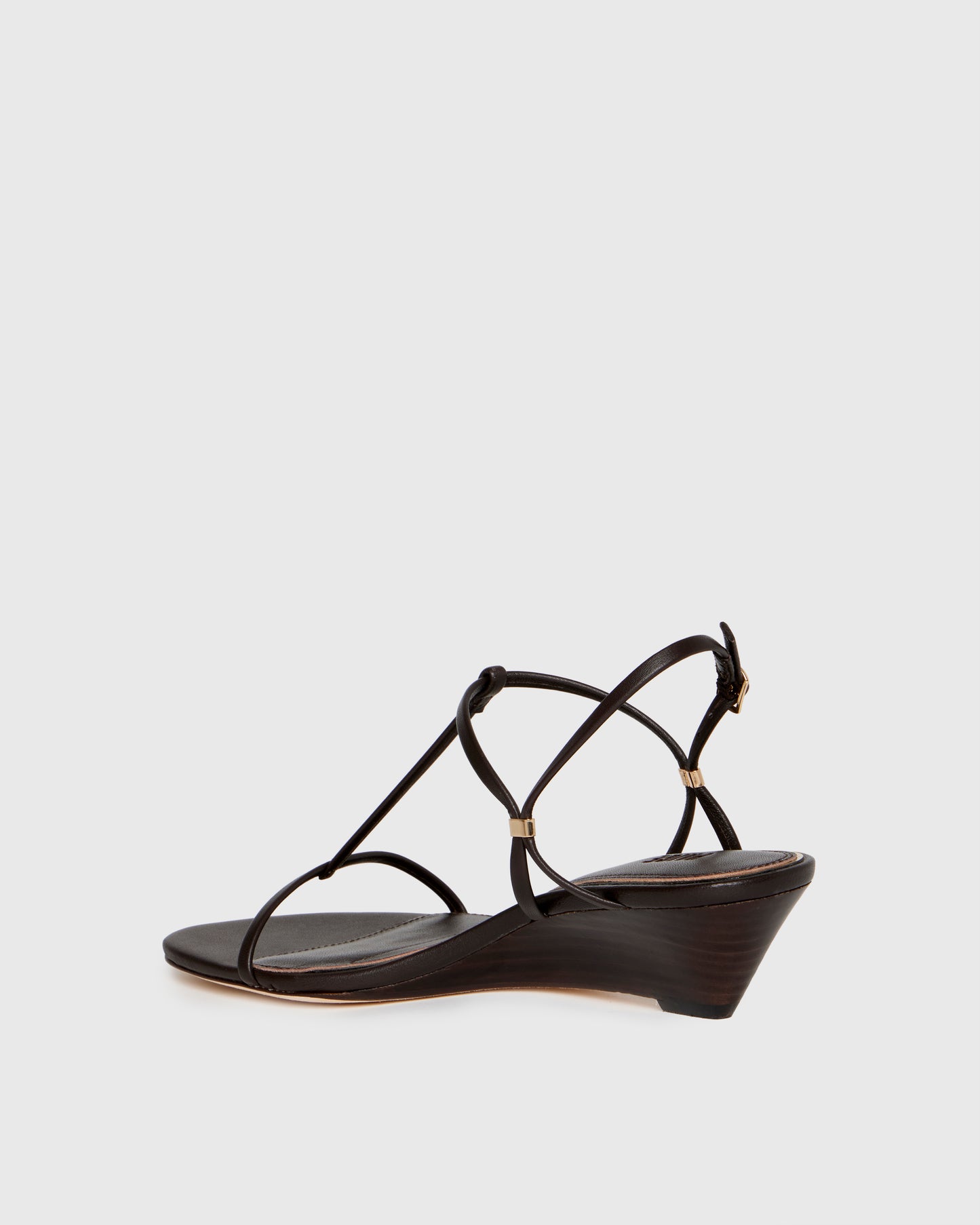Chocolate wedge sandal with thin straps on a light gray background